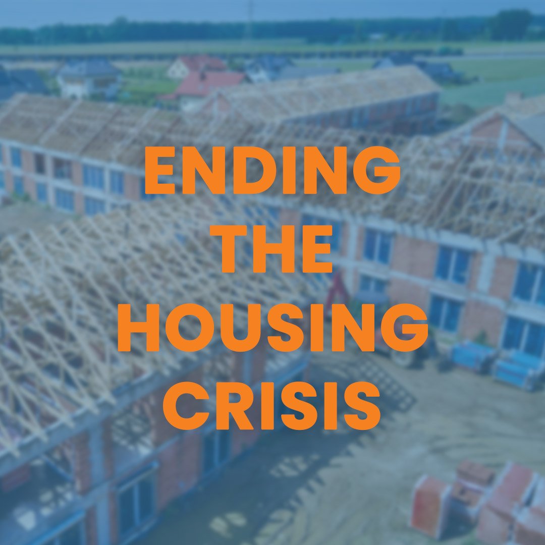 Aerial view of a housing development under construction with partially built houses and roofing structures, overlaid with orange text reading 'Ending the Housing Crisis'.