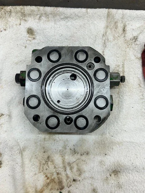 A metal mechanical component with multiple circular openings, positioned on a white cloth surface.