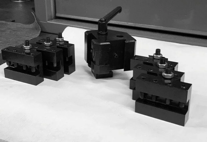 Black mechanical devices and parts on a white surface, with a window or glass pane in the background.