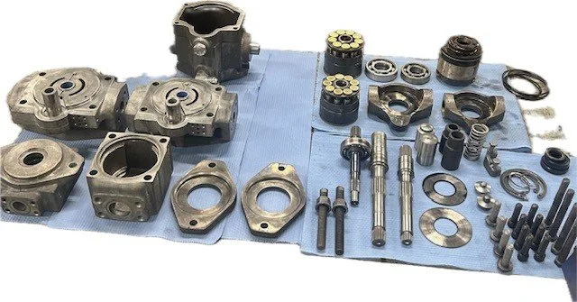 Various disassembled engine parts, including cylinder heads, pistons, valves, and bolts, laid out on blue cloth.