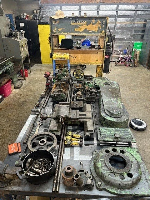 A workbench with disassembled mechanical parts, tools, and equipment in a workshop.