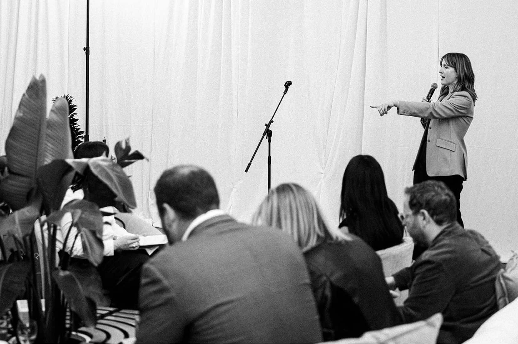 A woman giving a speech to a seated audience in a conference room.