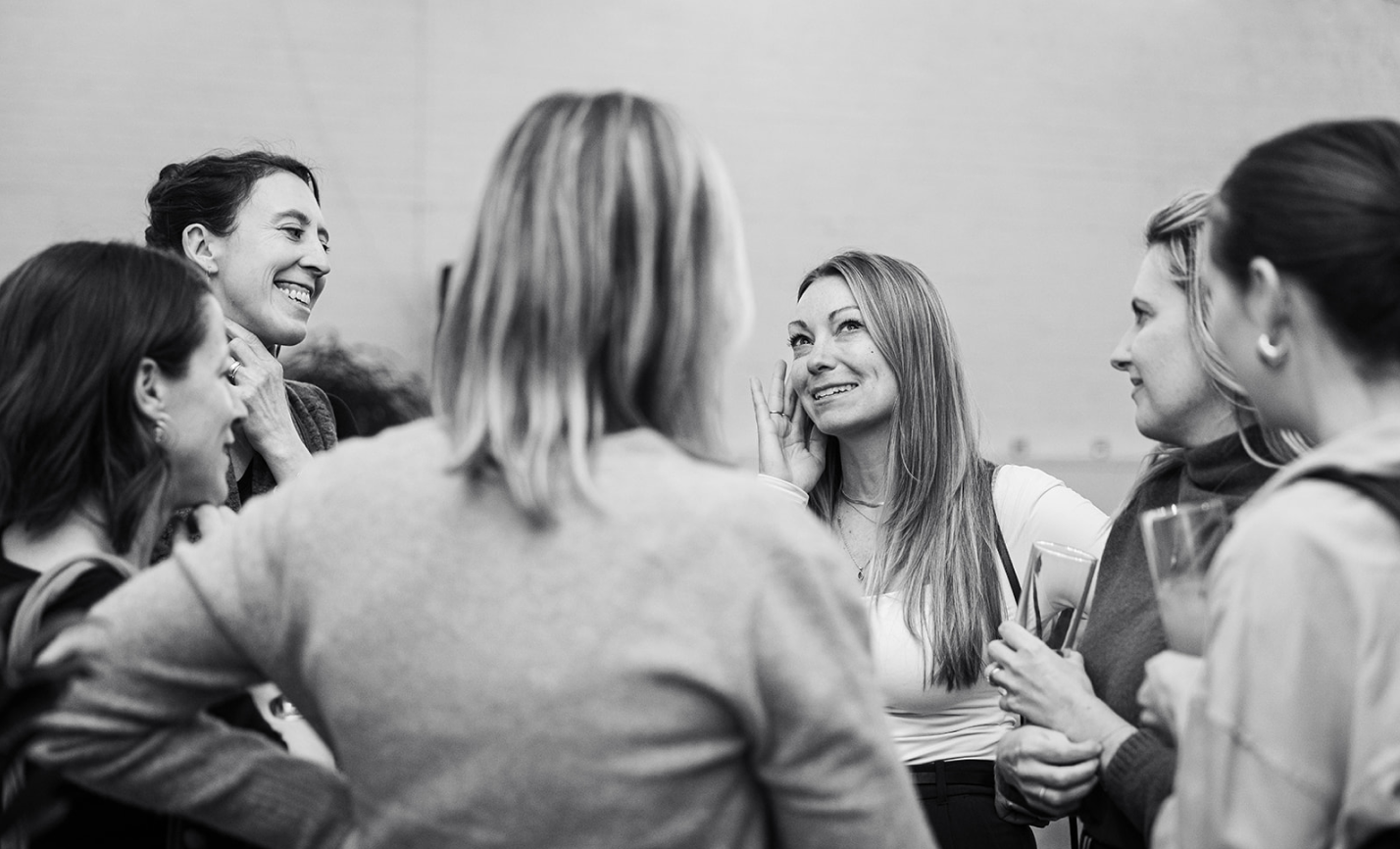 Group of women engaged in a lively conversation, smiling and laughing together.