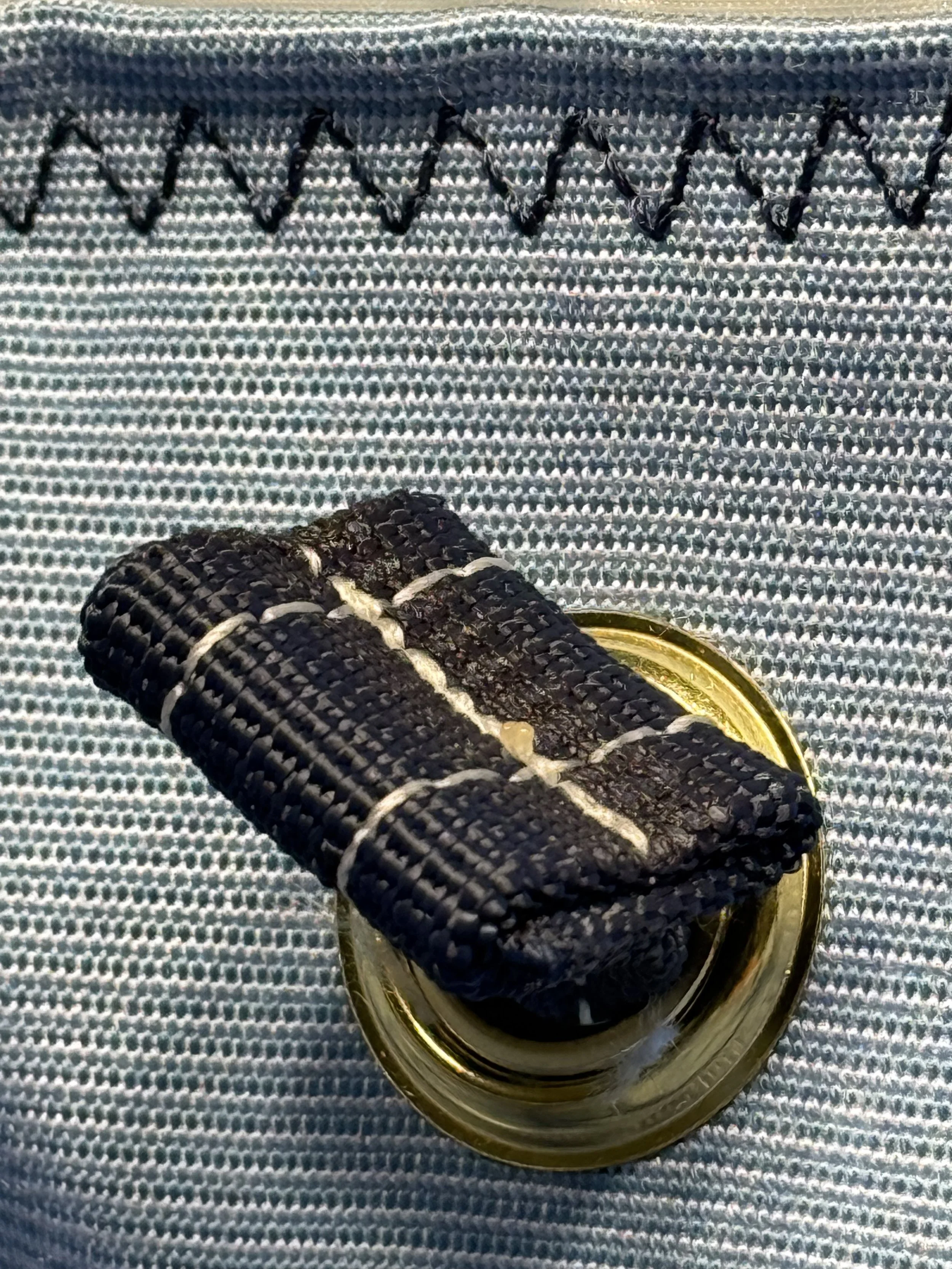 A pair of black sneakers with white soles placed on top of a glass jar filled with dark liquid, on a textured checkered surface.