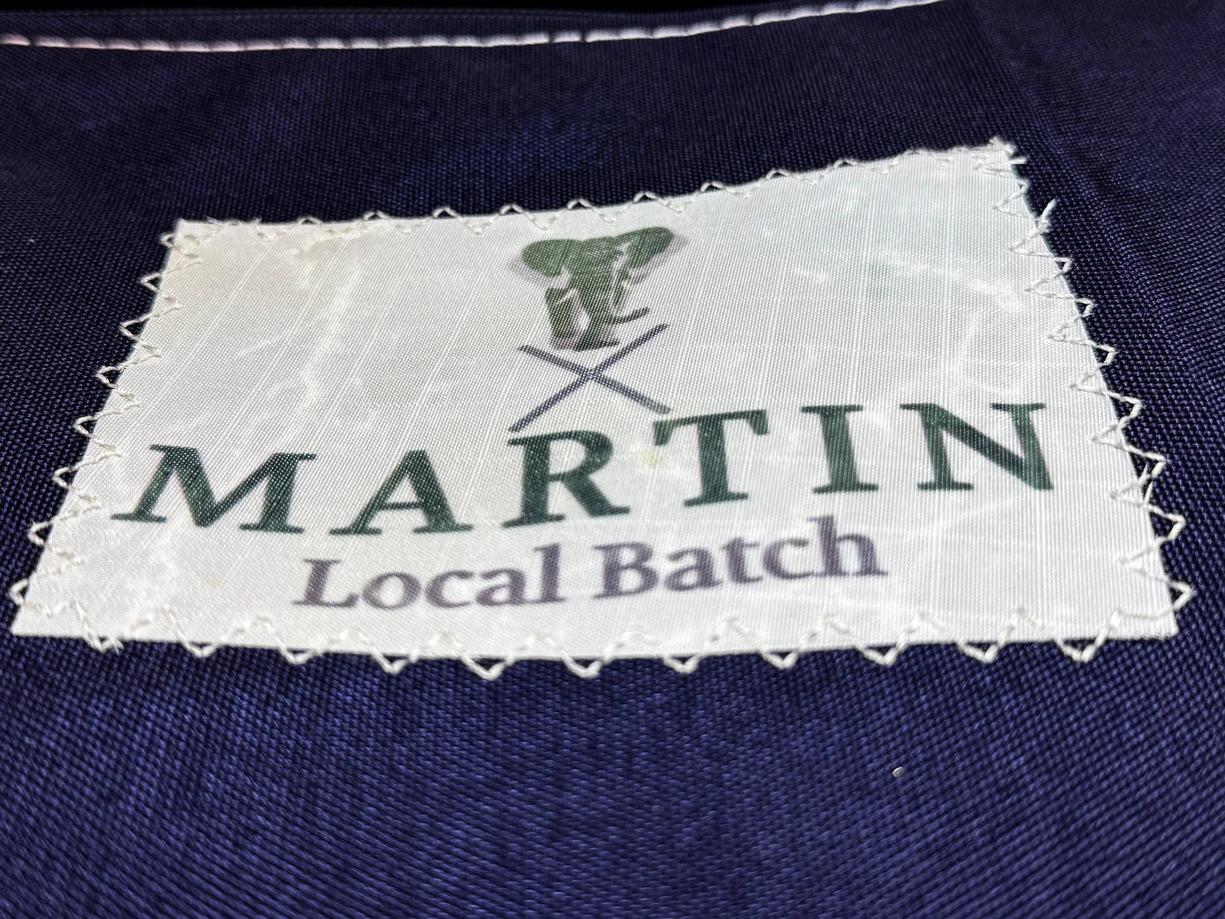 Close-up of a fabric label with the word 'MARITIN' and the phrase 'Local Batch,' stitched onto dark blue fabric.