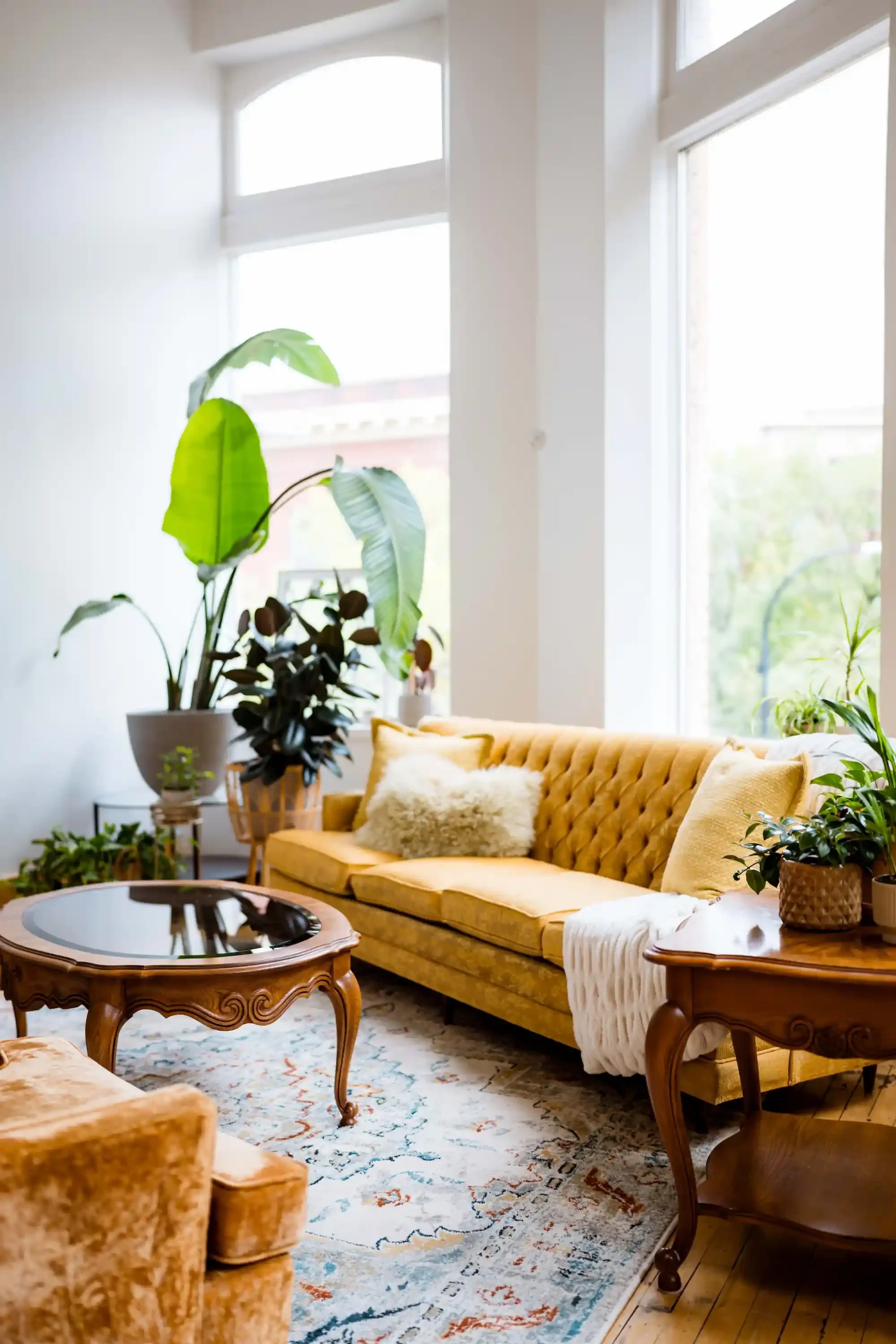 Lounge area at The Harlow Exchange wedding venue in Winnipeg featuring yellow tufted sofa, vintage furniture and natural light through arched windows
