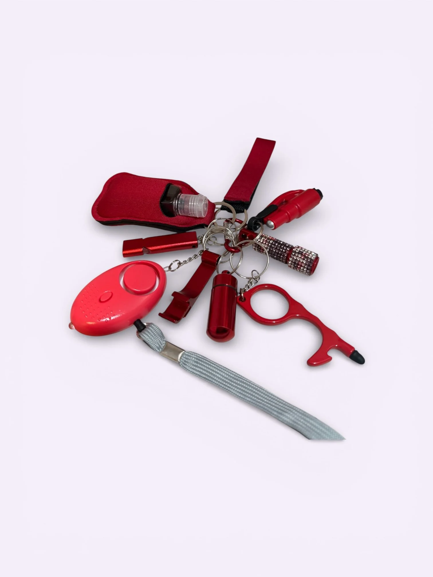 A collection of red items on a keychain, including a small knife, flashlight, whistle, and other small tools, all attached to a red fabric strap.