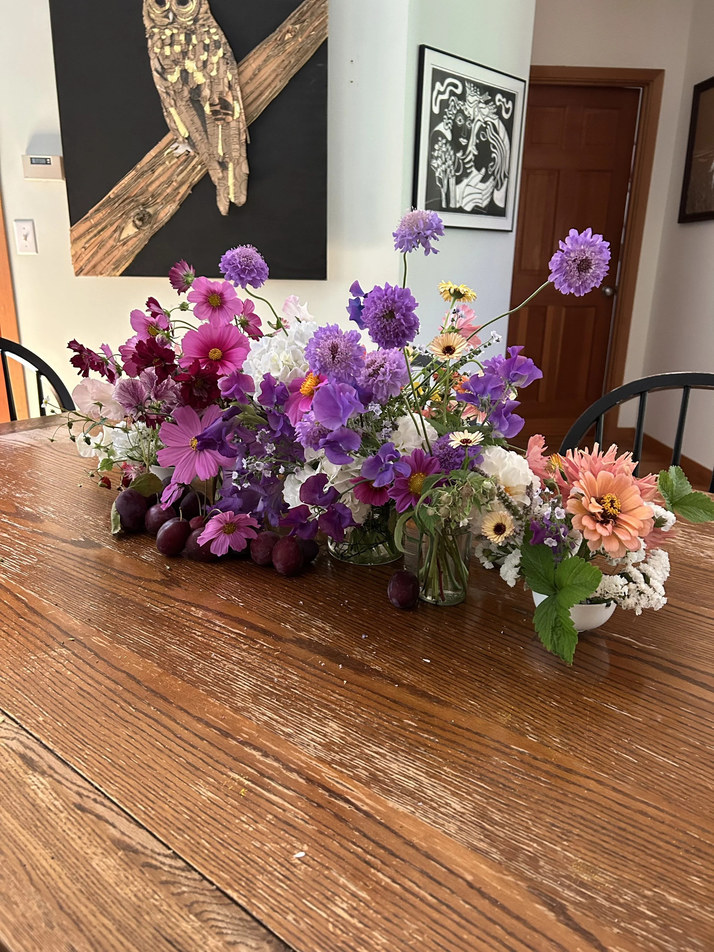 Colorful bouquet of various flowers including purple, white, pink, and peach blooms arranged on a wooden table.