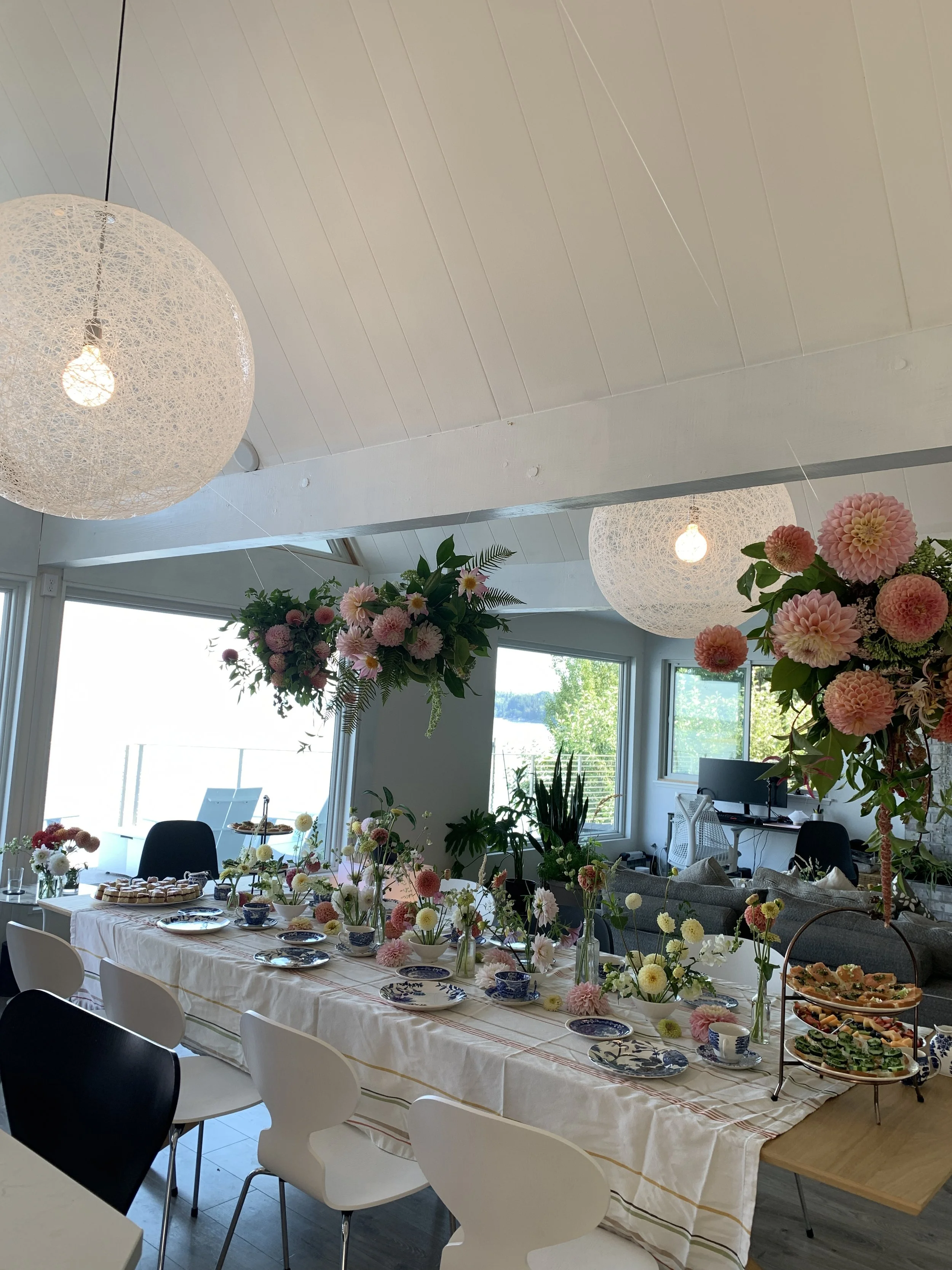 Spring decorated dining table with floral arrangements, plates, and pastries in a bright room with windows