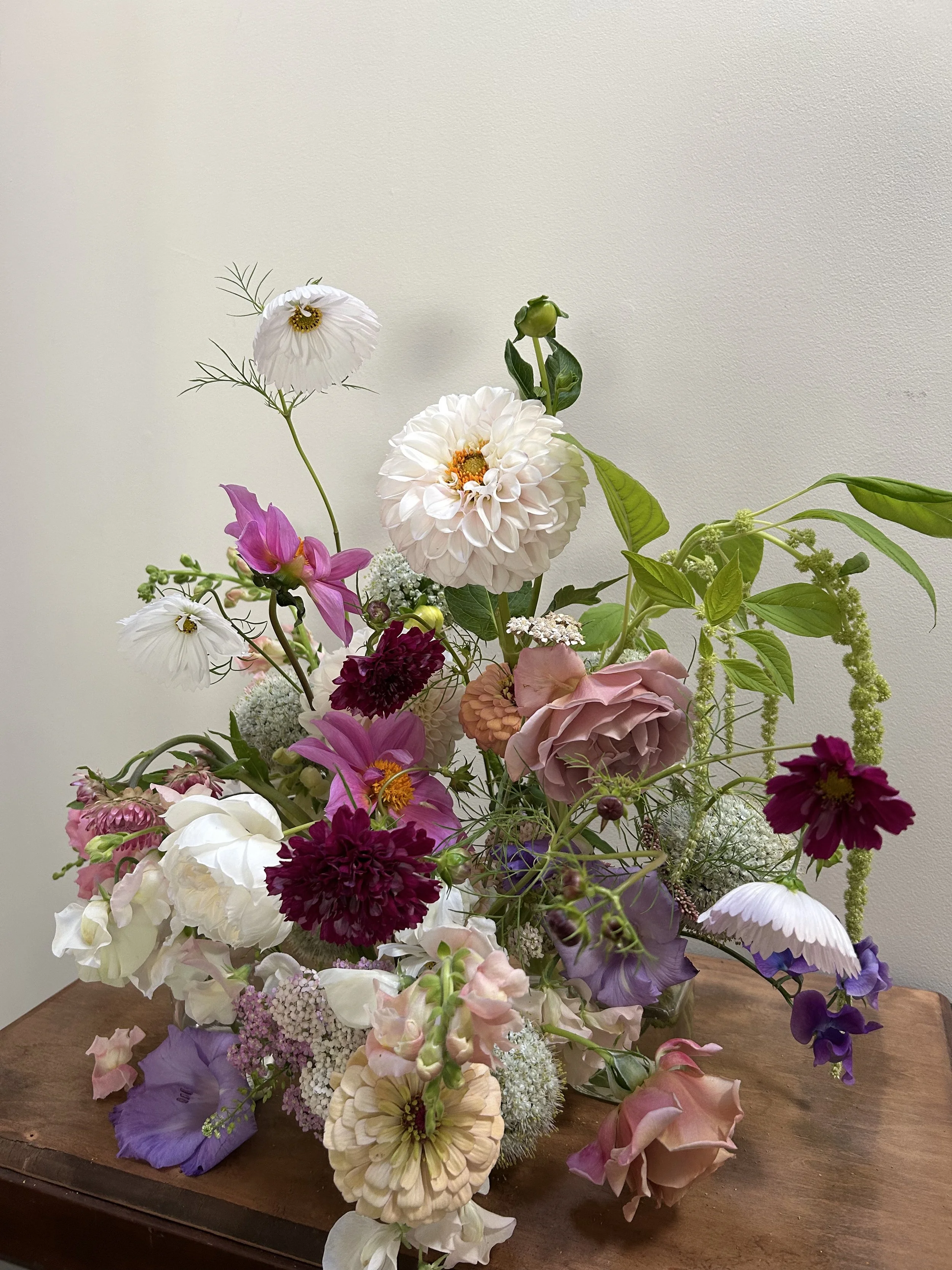 Colorful mixed flower bouquet with pink, purple, white, and cream blooms on a wooden surface