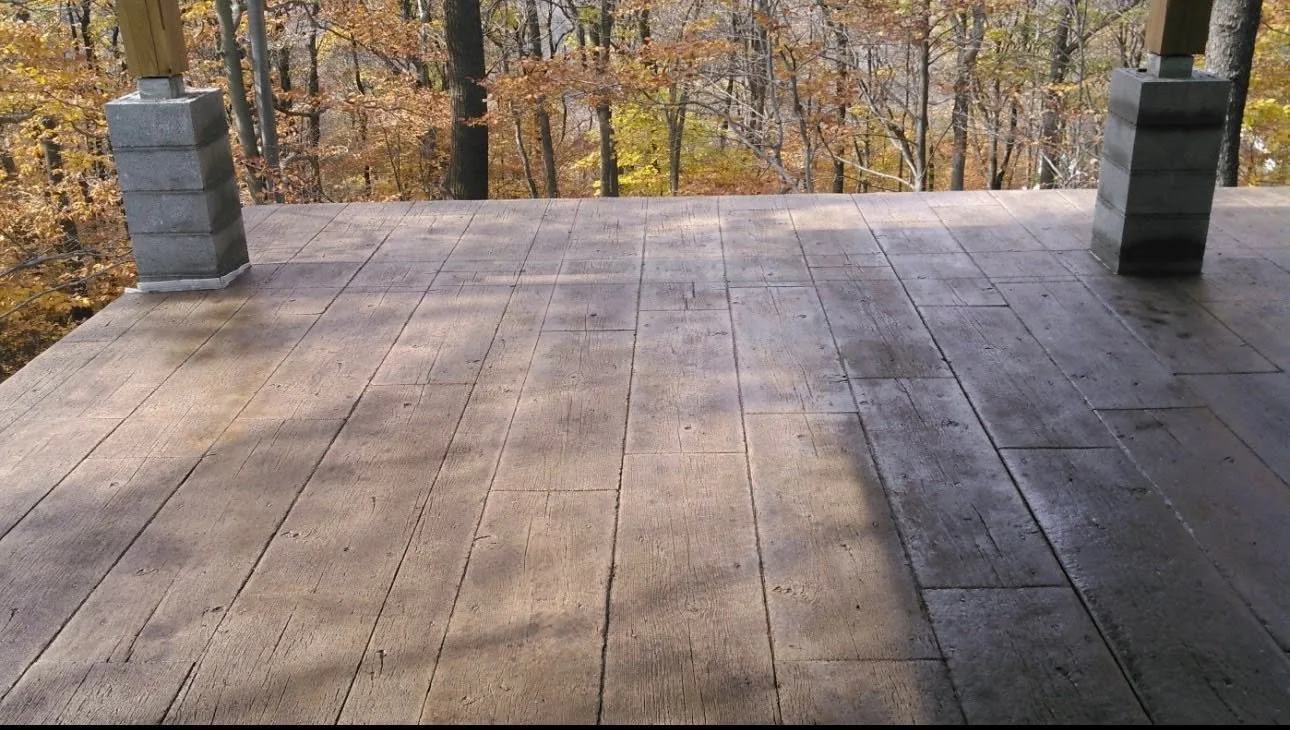 View from a wooden deck with four support posts, overlooking a forest with trees in autumn colors.