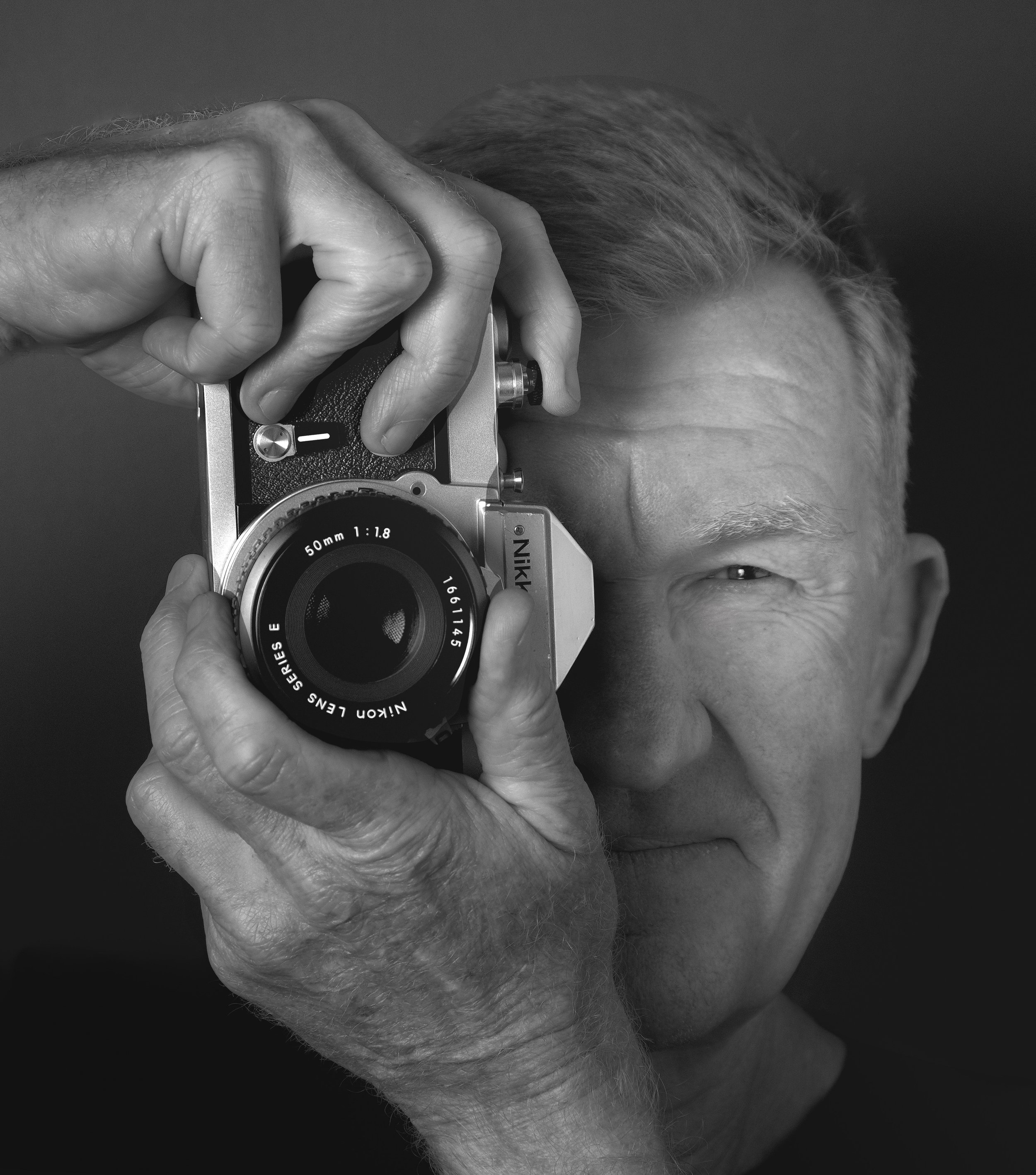 Black and white portrait of model holding vintage camera to eye