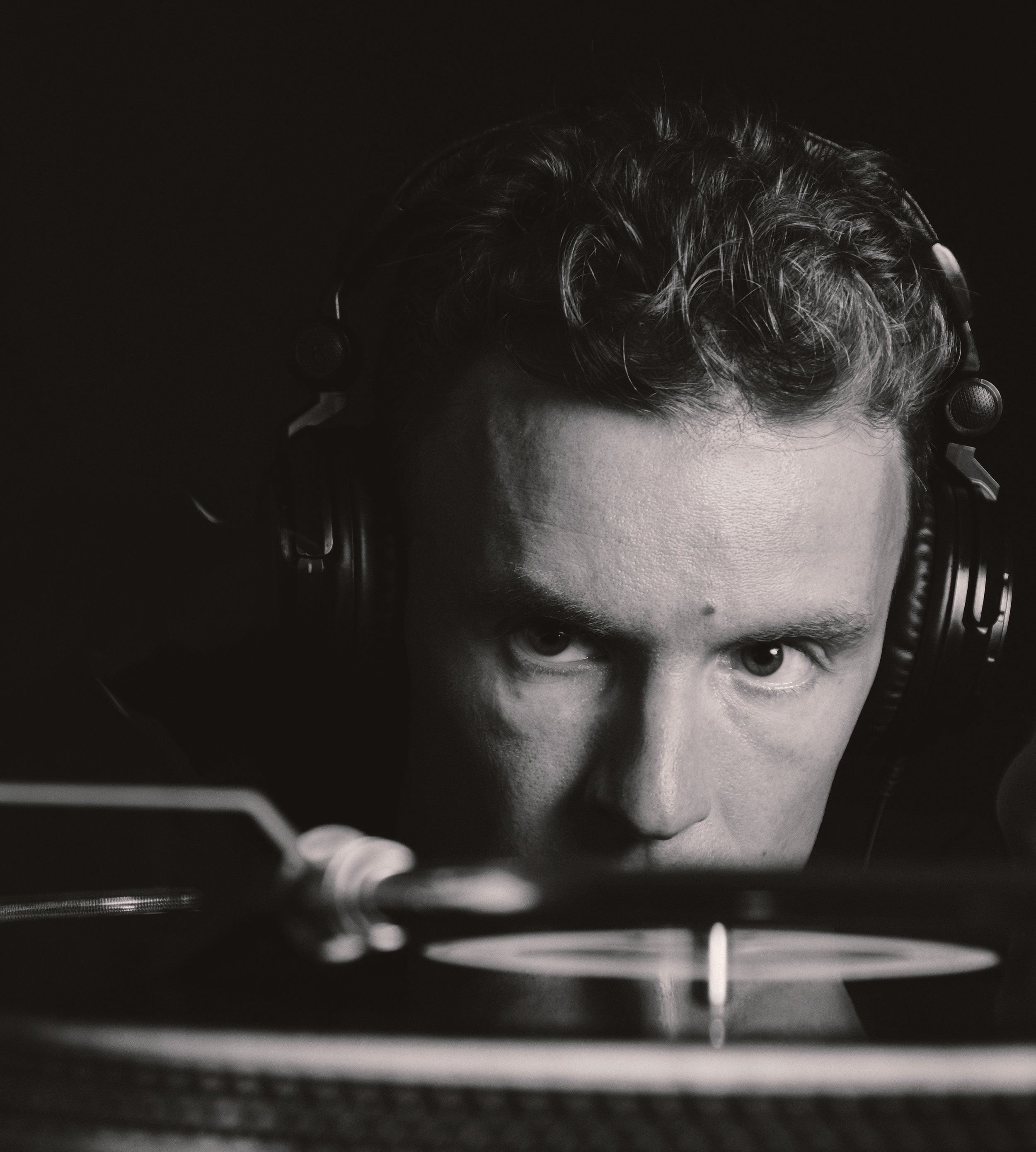 Black and White portrait of a DJ looking at a recored