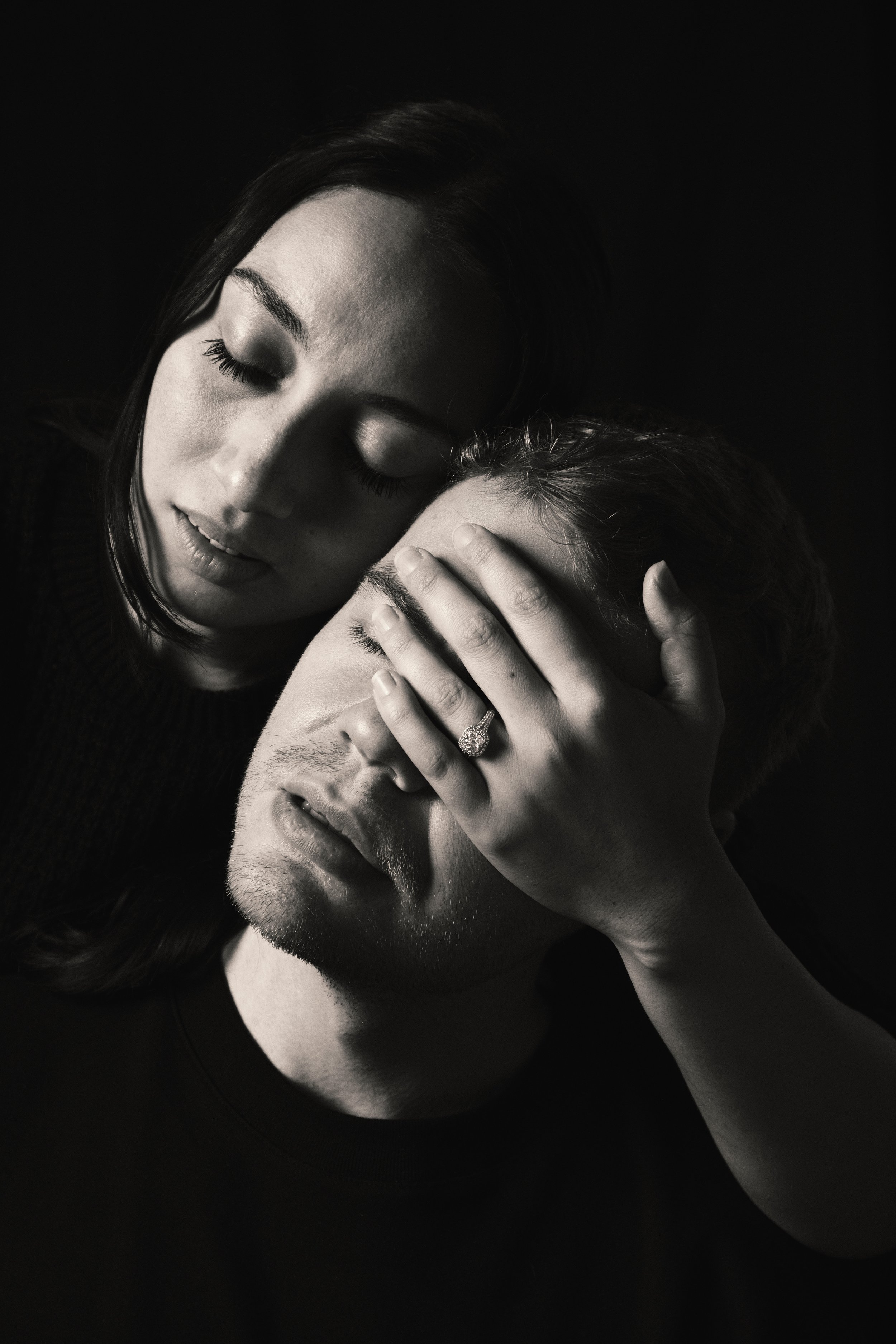 black and white portrait couple, she is holding his head, with the wedding ring showing
