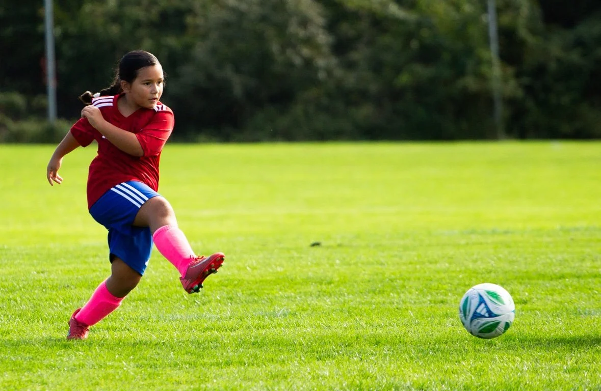 Girl striking the ball mid-kick — sports photography in Long Island