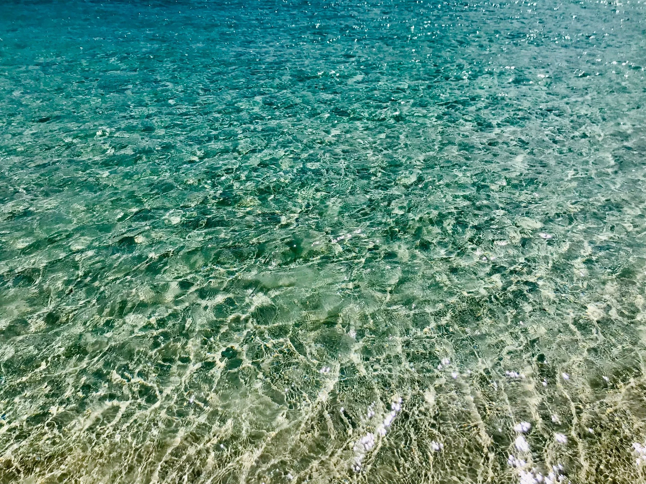 Clear turquoise water with sunlight creating shimmering reflections on the surface.