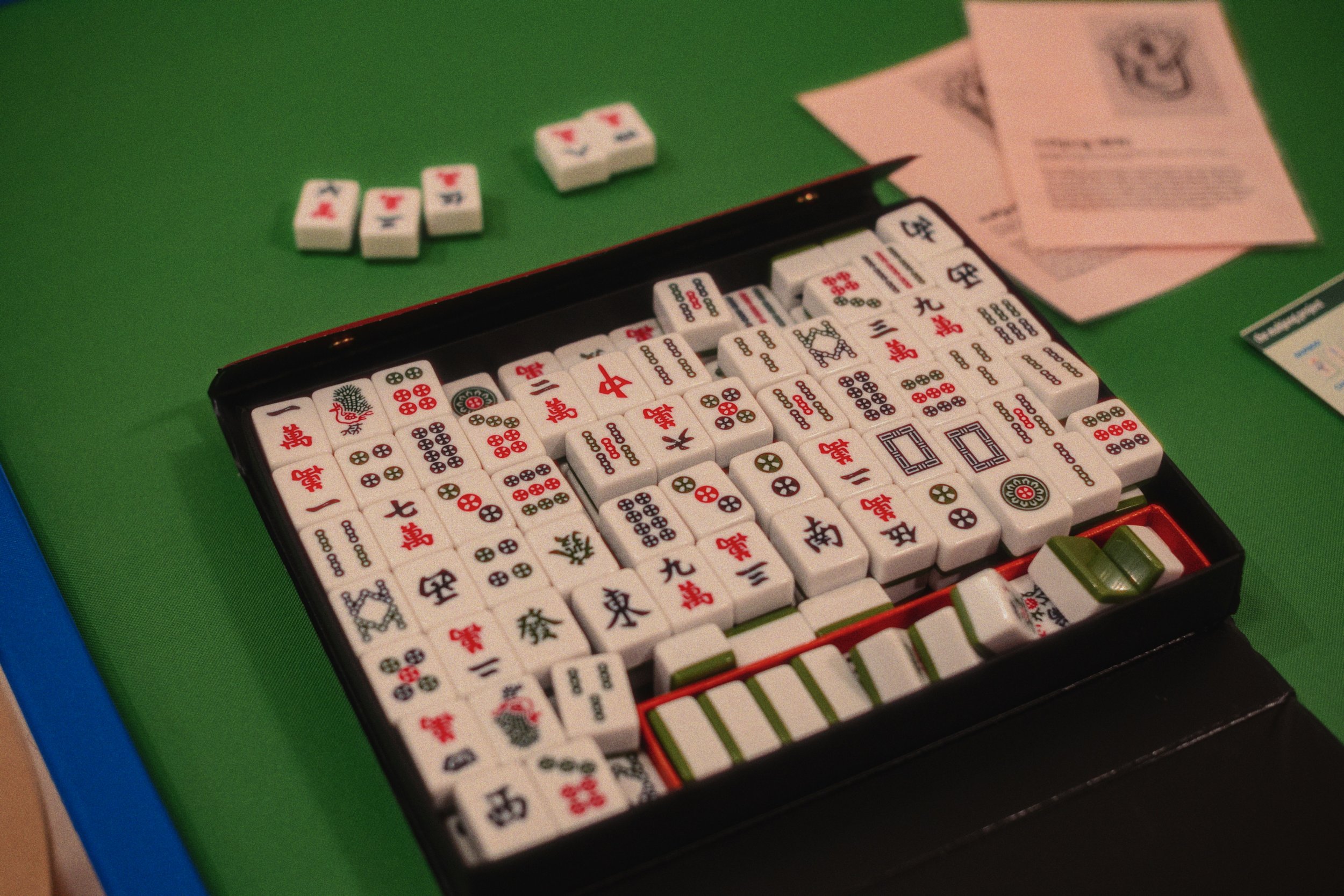 A Mahjong game setup with tiles and scored tiles on a green table.