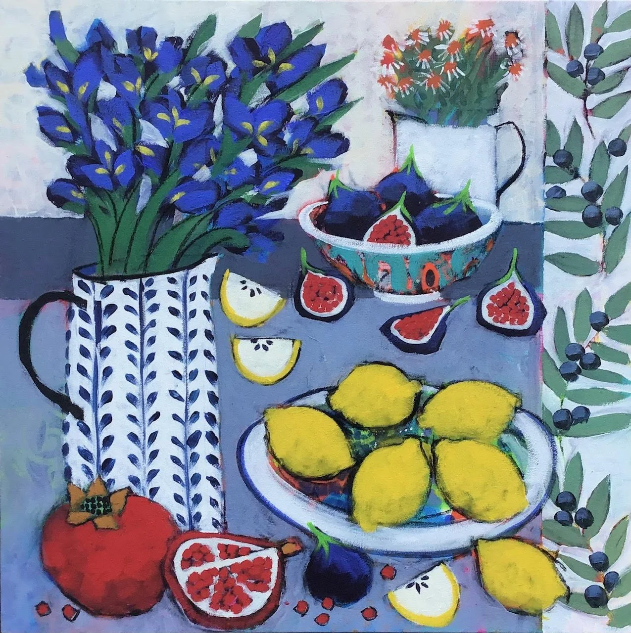 Painting of a still life with a bouquet of blue irises in a patterned white vase, scattered lemons, pomegranate, figs, and sprigs of berries on a table, with a white pitcher and a floral background.