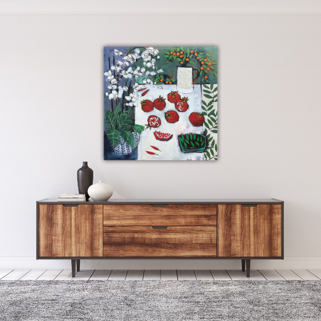 A modern wooden sideboard decorated with a dark brown vase, a white vase, and a couple of books, with a colorful abstract still life painting of pomegranates, green leaves, and flowers hanging above it in a minimalist room.
