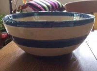 Ceramic bowl with blue and white horizontal stripes on a wooden surface.
