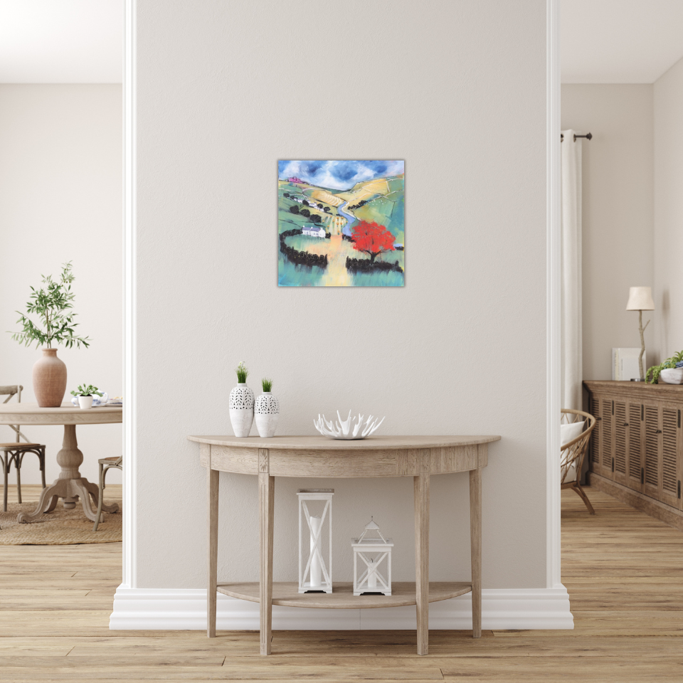 Interior of a home featuring a hallway with a wooden console table decorated with white vases and lanterns, and a colorful landscape painting on the wall. To the left, a dining area with a wooden table, chairs, and potted plant. To the right, a partial view of a room with a sideboard and lamp.