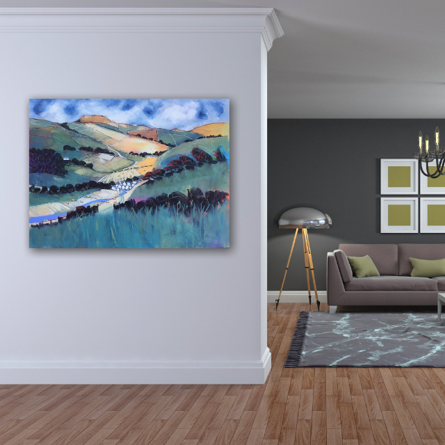 Colorful landscape painting of hills, trees, and a blue sky hanging on a white wall in a modern living room