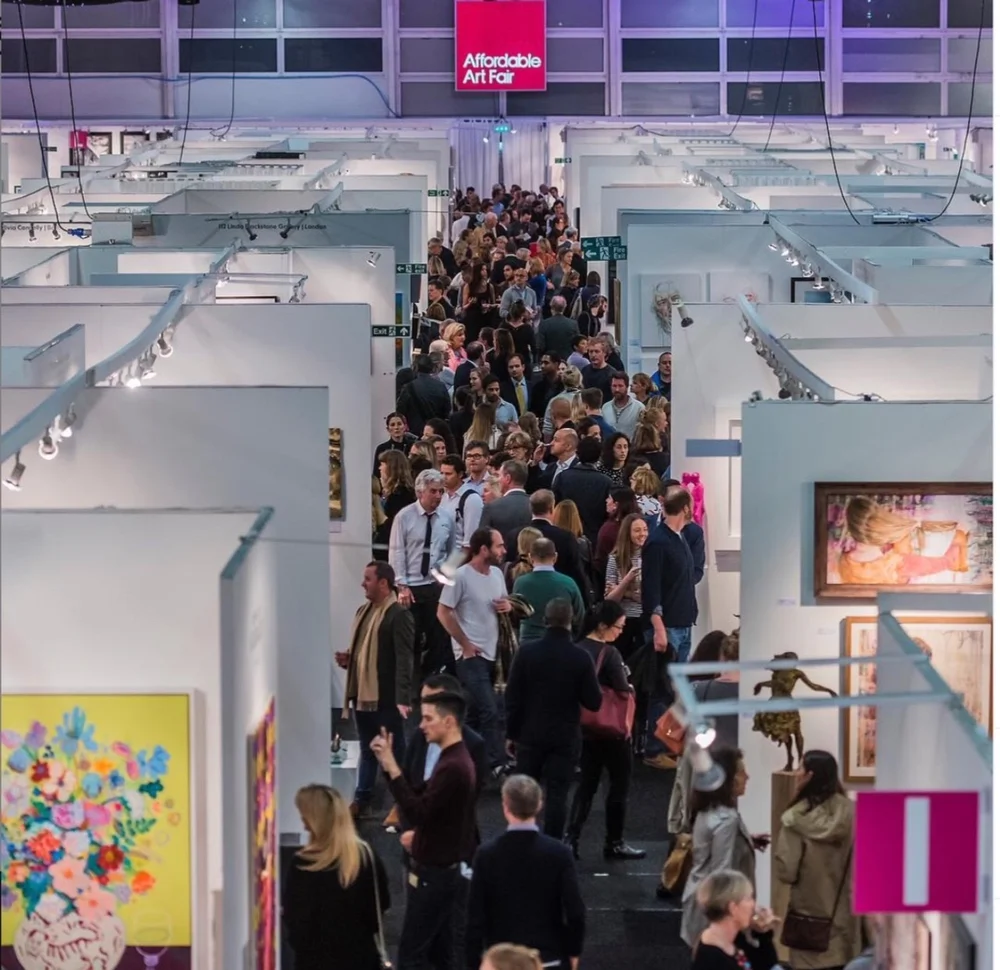 Crowd of people walking through art booths at an art fair.