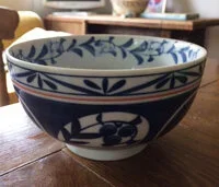 Decorative ceramic bowl with blue and white floral patterns, on a wooden surface.