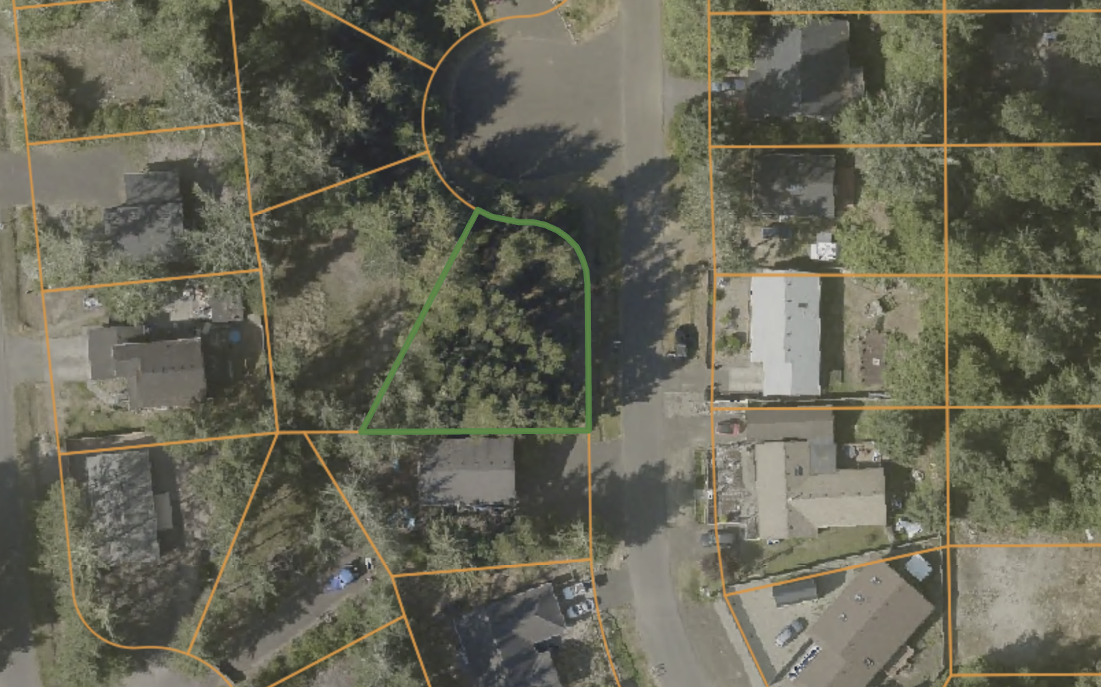 An aerial view of a residential neighborhood with a large backyard outlined in green, surrounded by other houses and trees, overlaid with orange property boundary lines.
