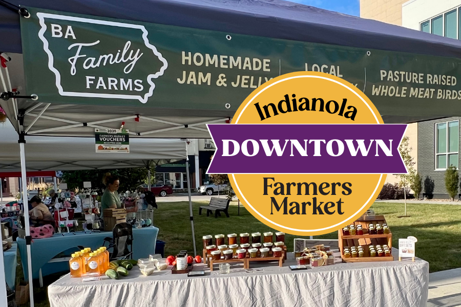 A vendor stall at the Indiana Downtown Farmers Market selling homemade jam and jelly, with canisters and jars on display, under a green tent that reads "BA Family Farms," advertising local, pasture-raised whole meat birds.