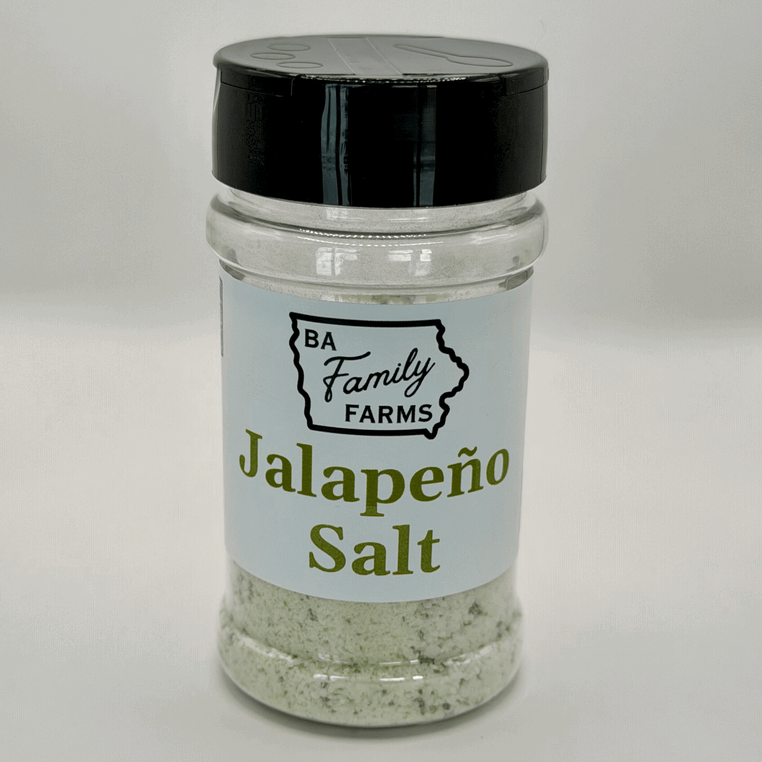 A clear plastic jar with a black lid containing jalapeño salt from BA Family Farms, pictured against a plain white background.