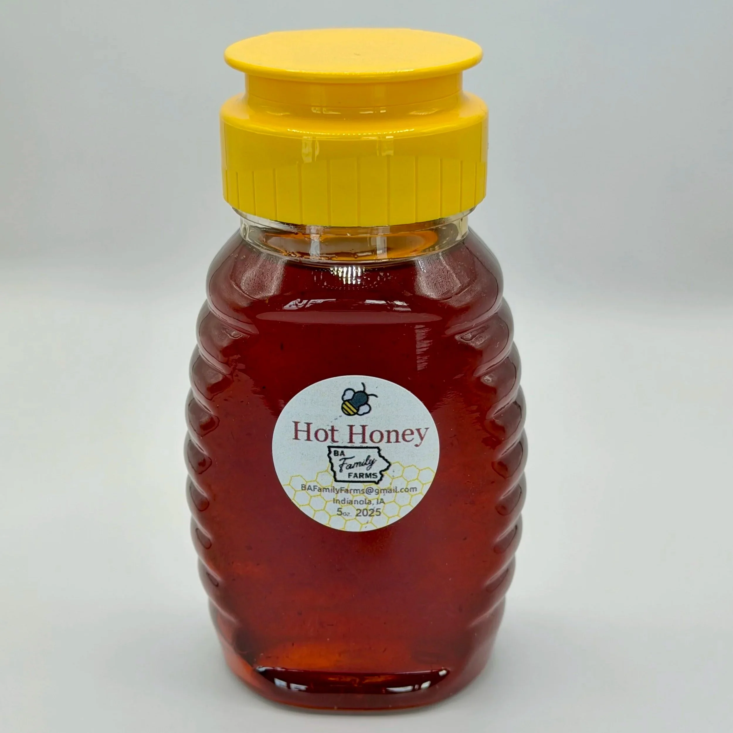Clear plastic jar of hot honey with a yellow lid, labeled with a bee illustration and text, from Family Farms in Indiana.