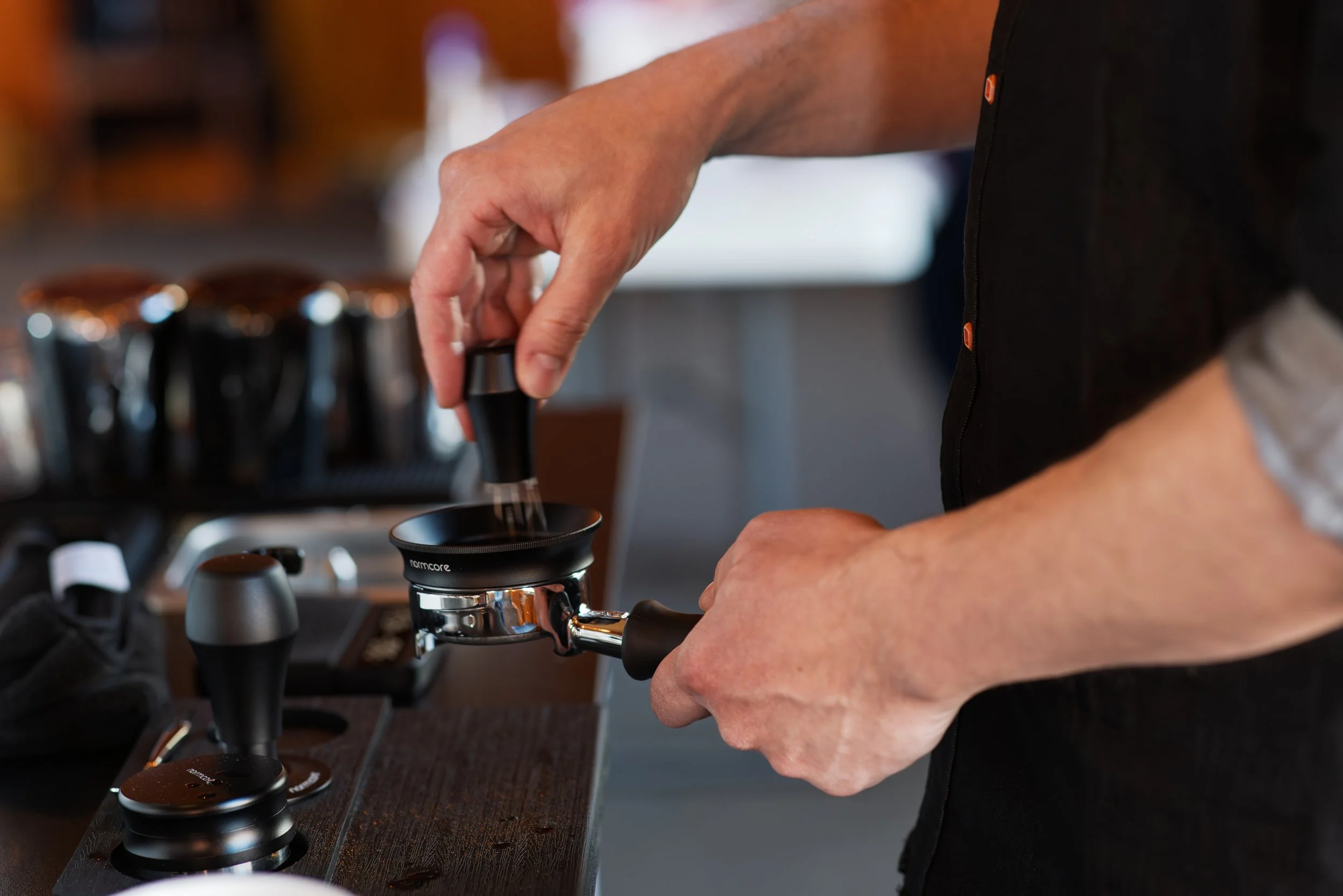 A barista with Preamble Coffee Cart in Fort Wayne, Indiana expertly preparing espresso by tamping coffee in a portafilter.