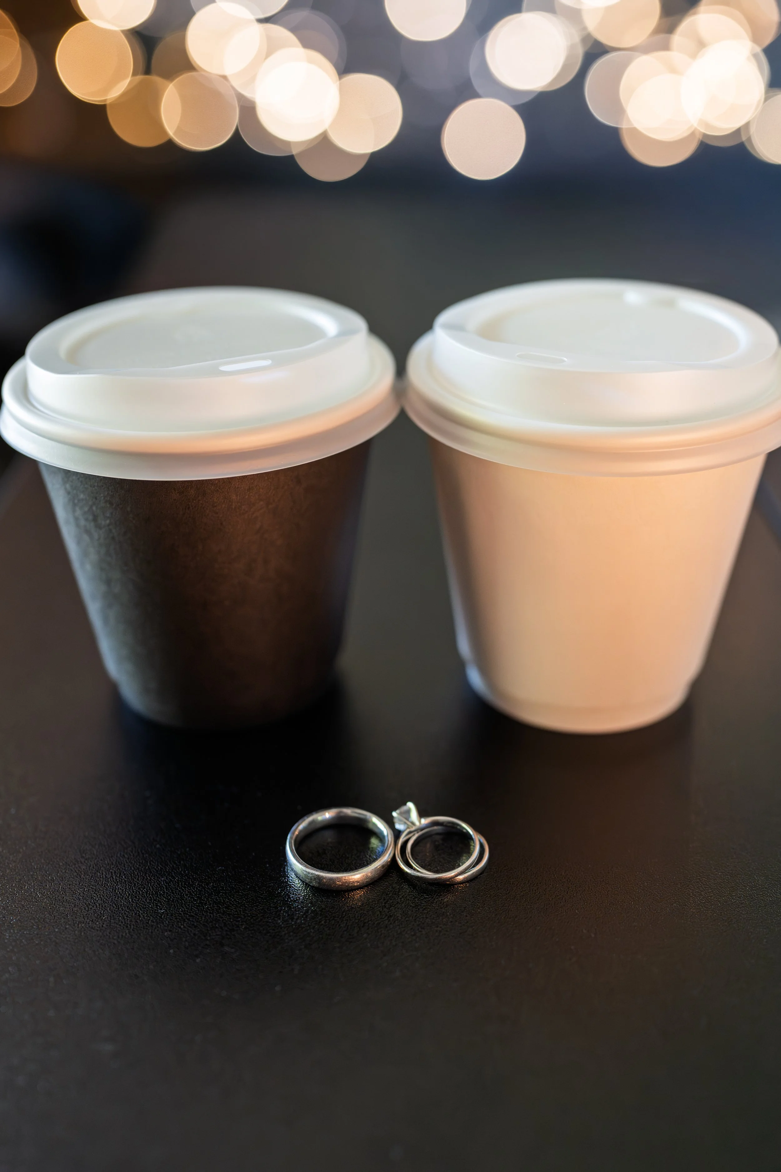 Wedding rings in front of a groom and bride's coffee cups from Preamble Coffee Cart Catering Mobile Espresso Bar in Fort Wayne, Indiana.