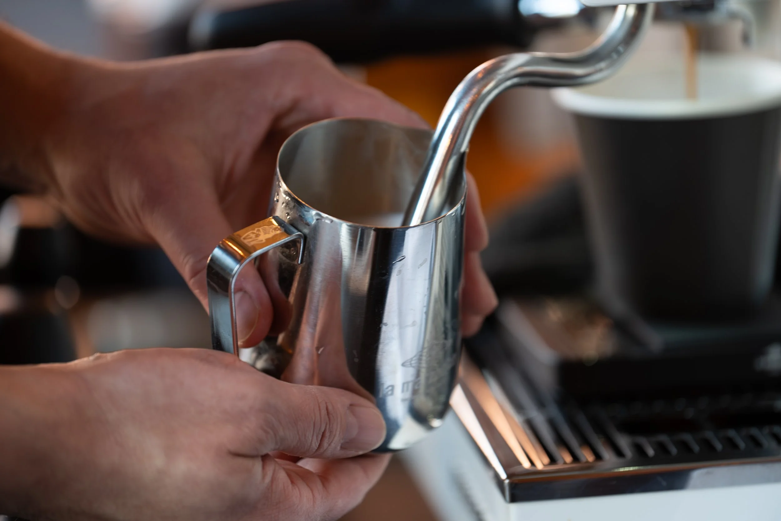 A barista with Preamble Coffee Cart in Fort Wayne, Indiana expertly steaming milk to create a latte with beautiful latte art for a guest