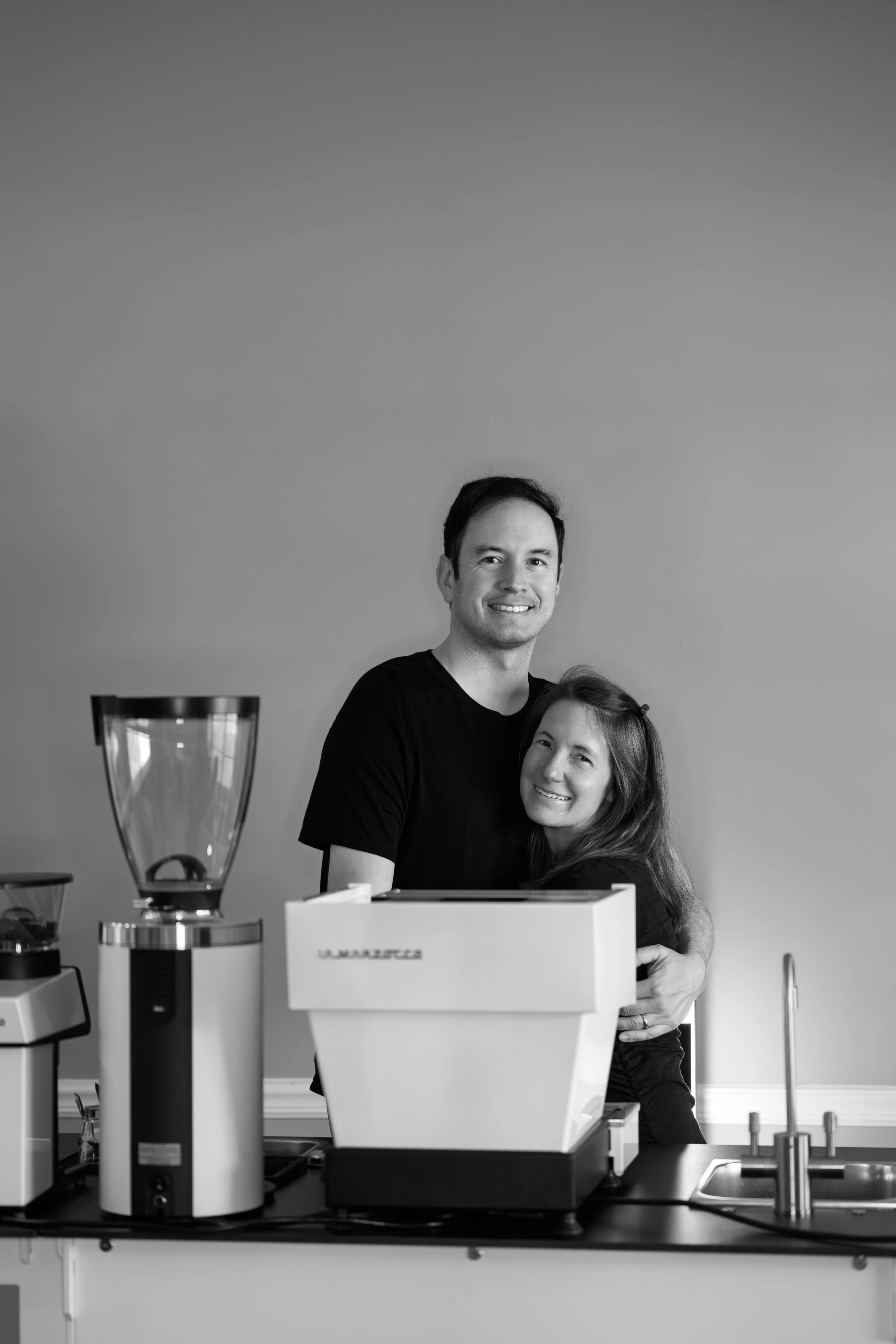 Mark and Katie, owners of Preamble Coffee standing with their coffee cart while smiling and welcoming guests to become customers.