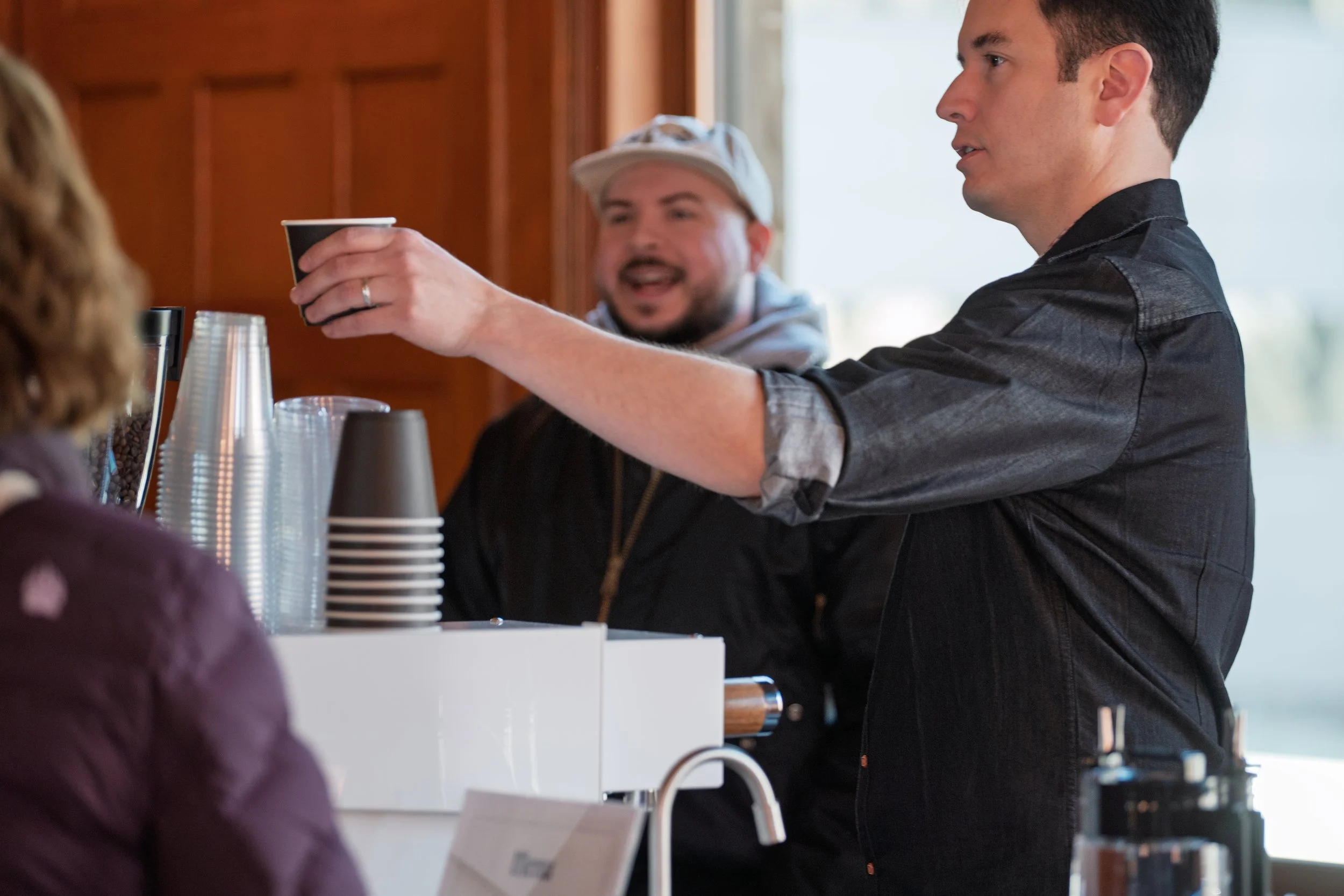 Owner Mark Pape of Preamble Coffee Cart Catering in Fort Wayne, Indiana serving a premium hot latte to a guest while another guest smiles in the background.