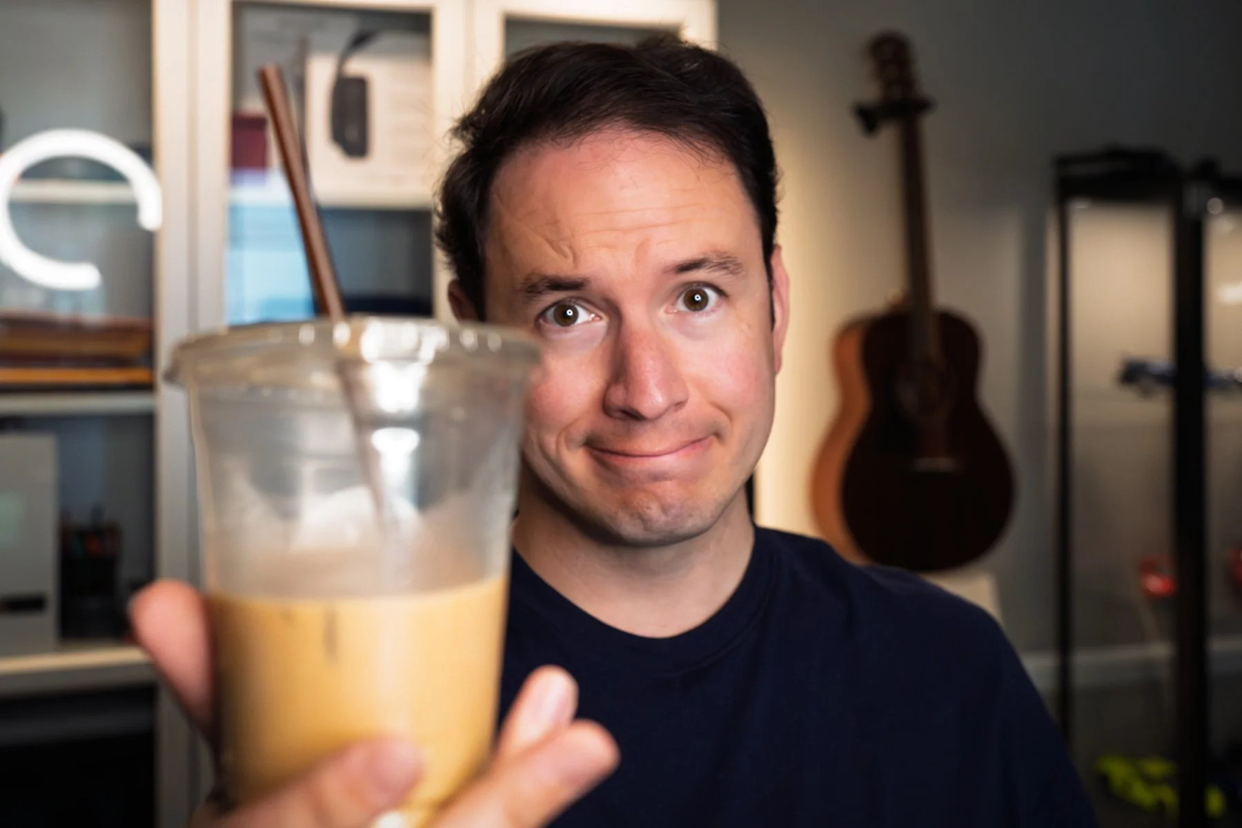 A barista and the owner of Preamble Coffee cart happily holding up an iced latte while displaying a fun and welcoming expression on his face.