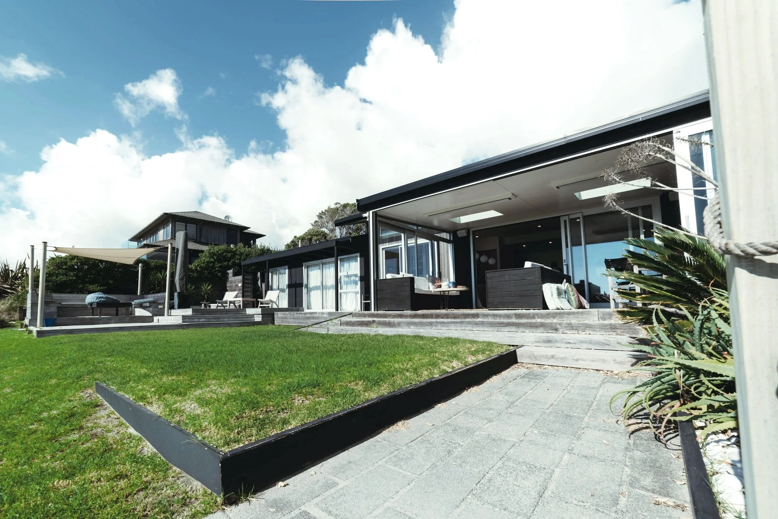 Modern house with outdoor patio and lawn under a partly cloudy sky