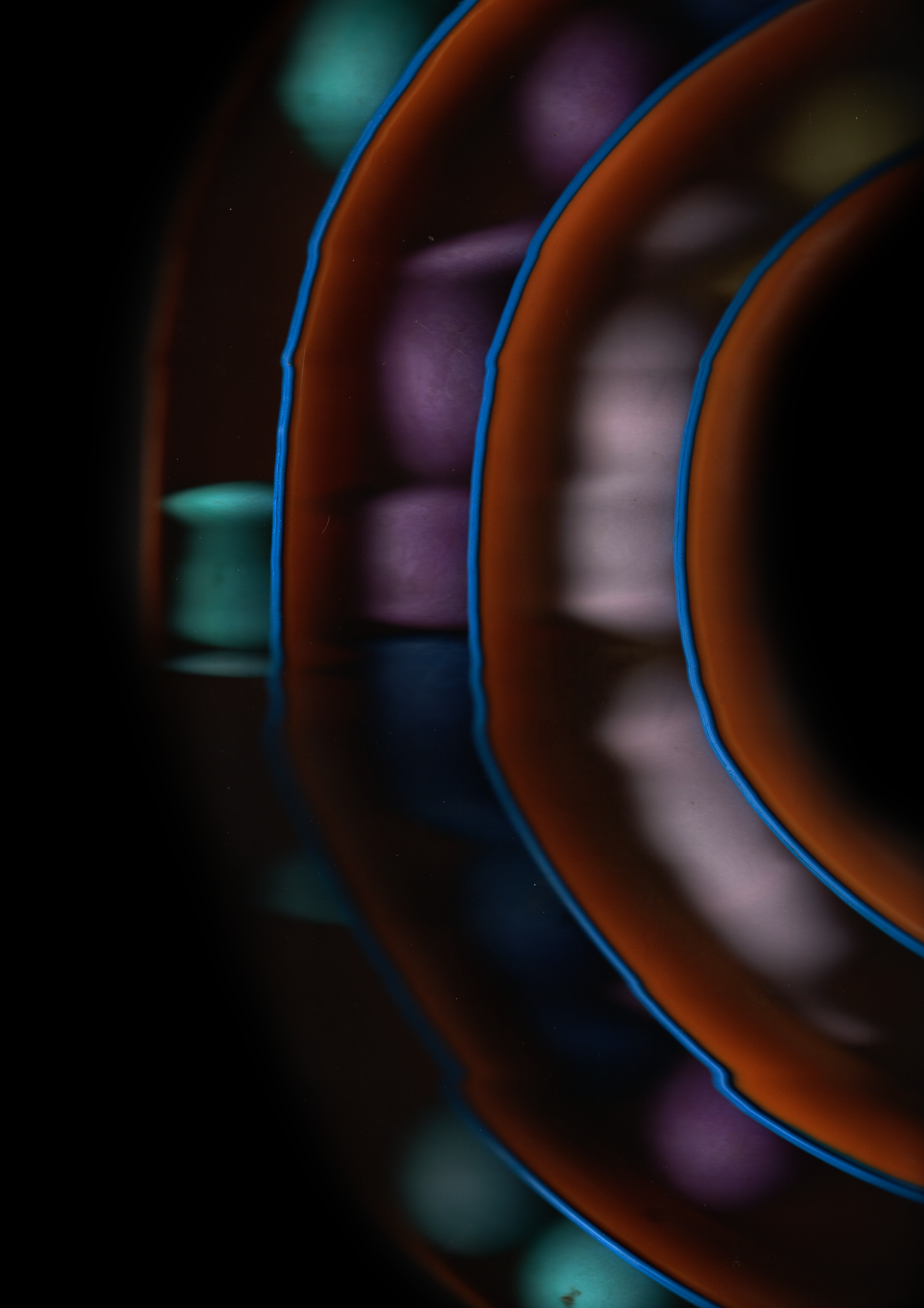 Close-up of colorful neon lights creating curved lines and reflections on a dark surface.