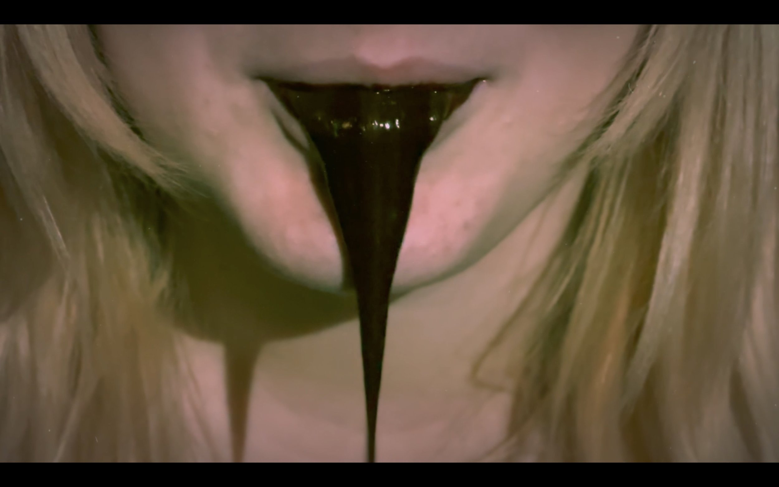 A close-up of a person's mouth with black liquid dripping from it.