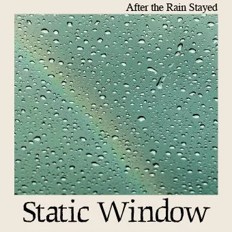 Close-up of a rain-covered window with water droplets and a faint rainbow in the background.