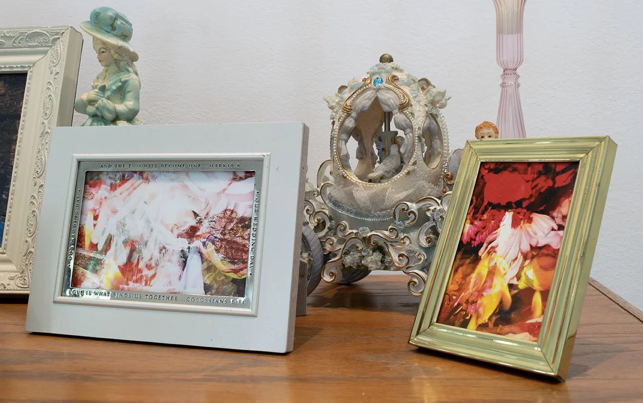 Decorative items on a wooden surface including framed photographs, a ceramic crown, and a porcelain figurine of a girl in a hat.