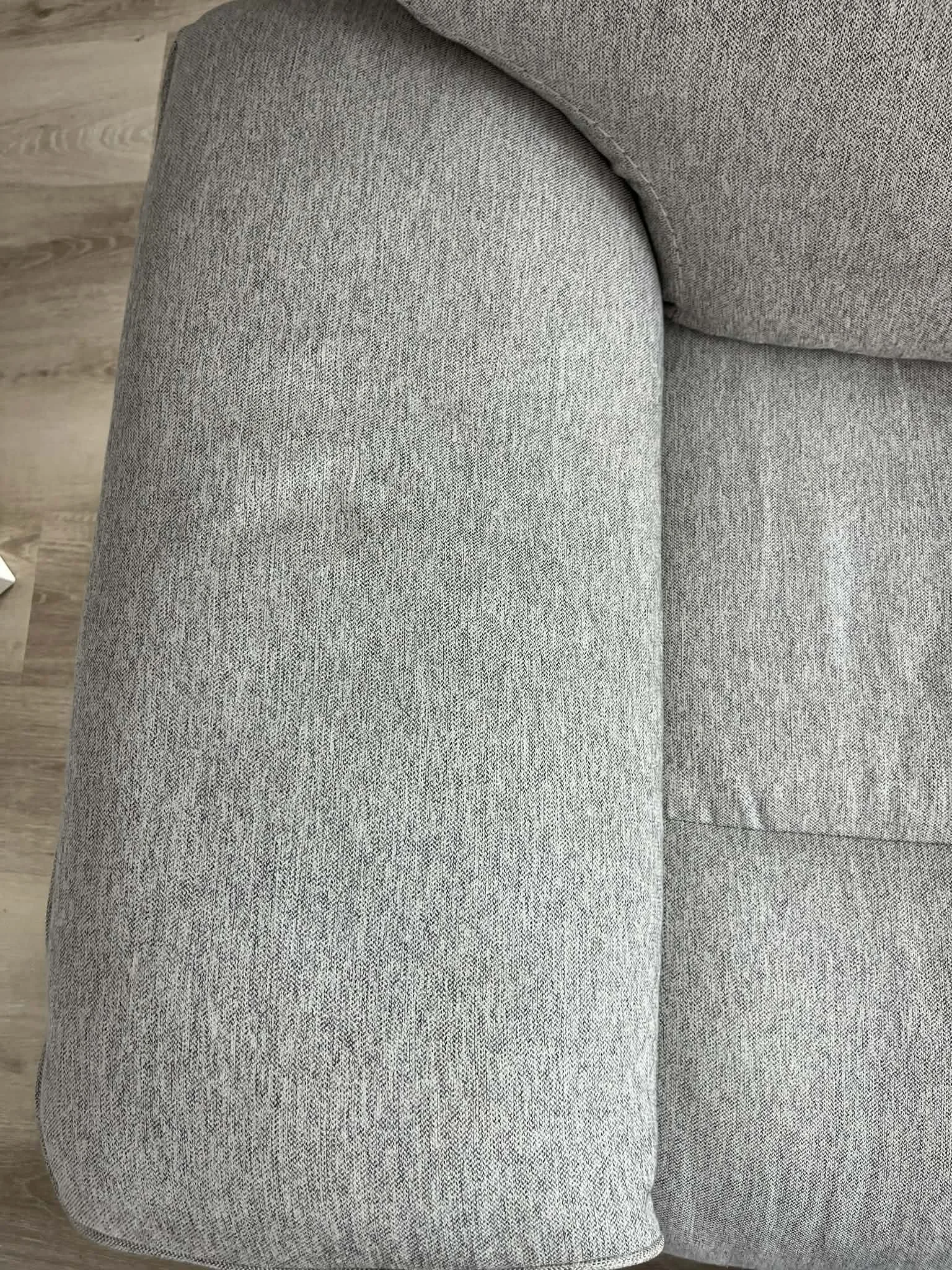 Close-up of a grey fabric upholstered sofa armrest.
