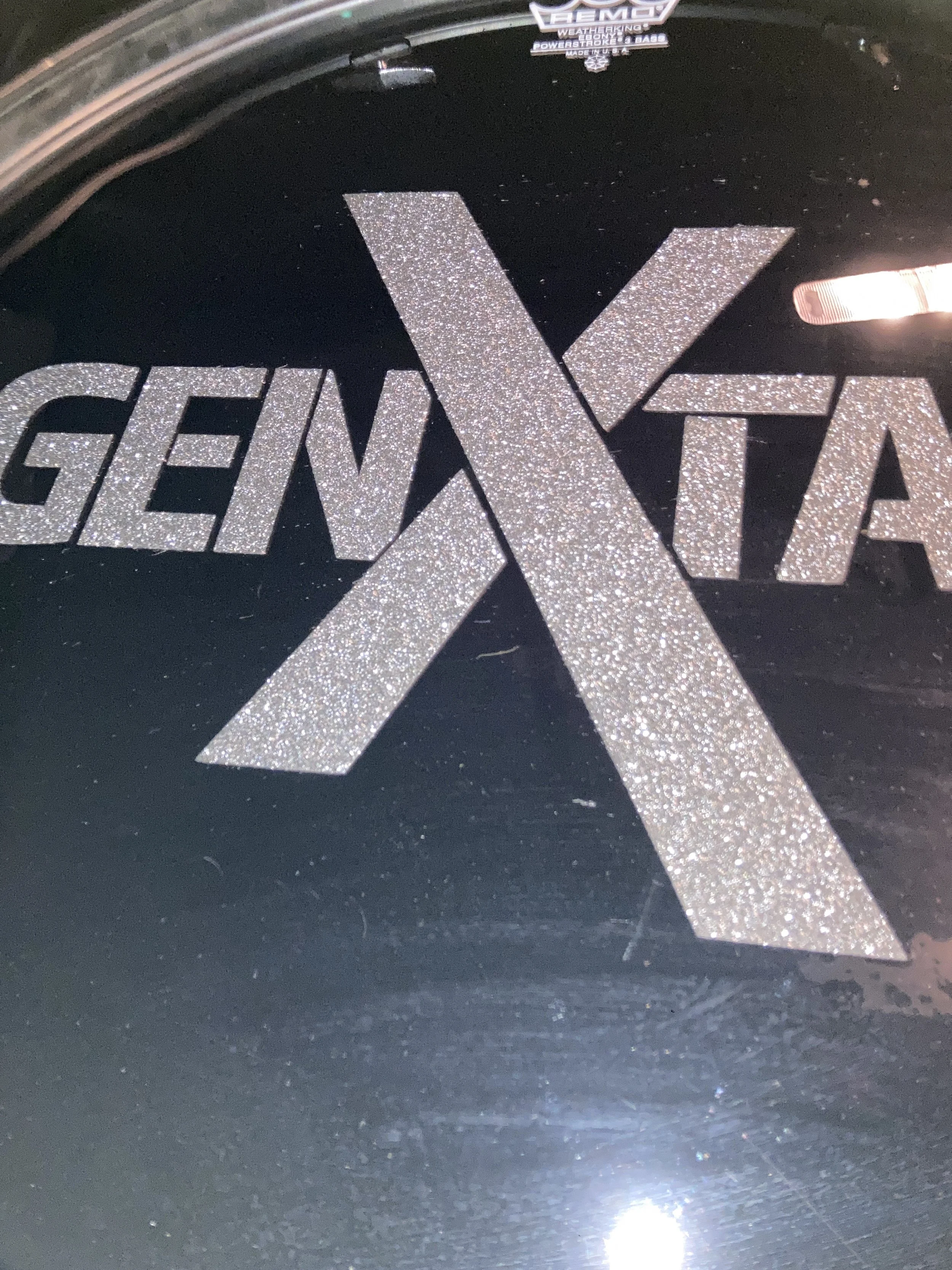 Sparkly silver decal with the word "Genuine" and a large X, applied inside a vehicle's windshield.