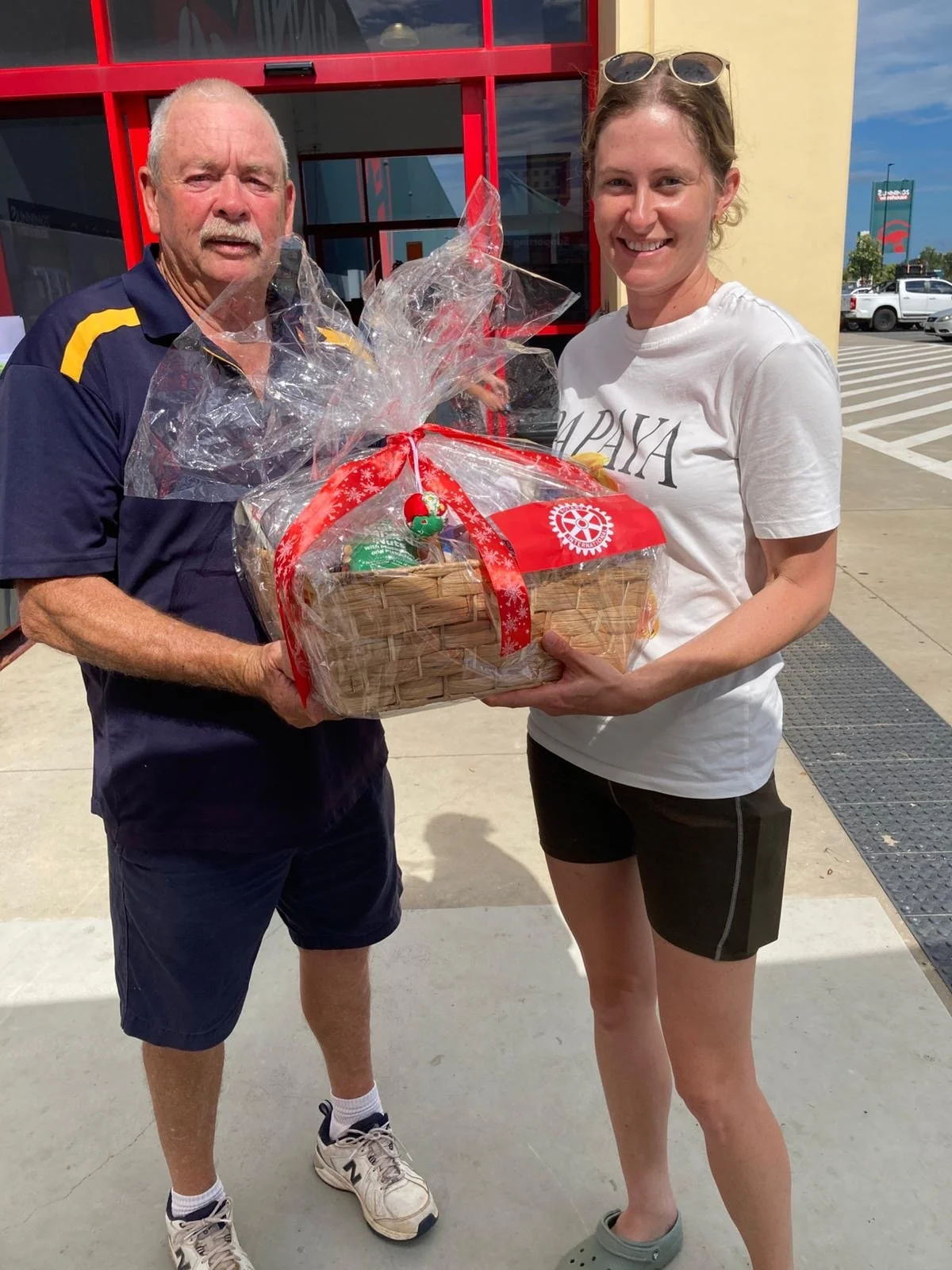 A male Rotary member and a young woman hold a holiday gift basket