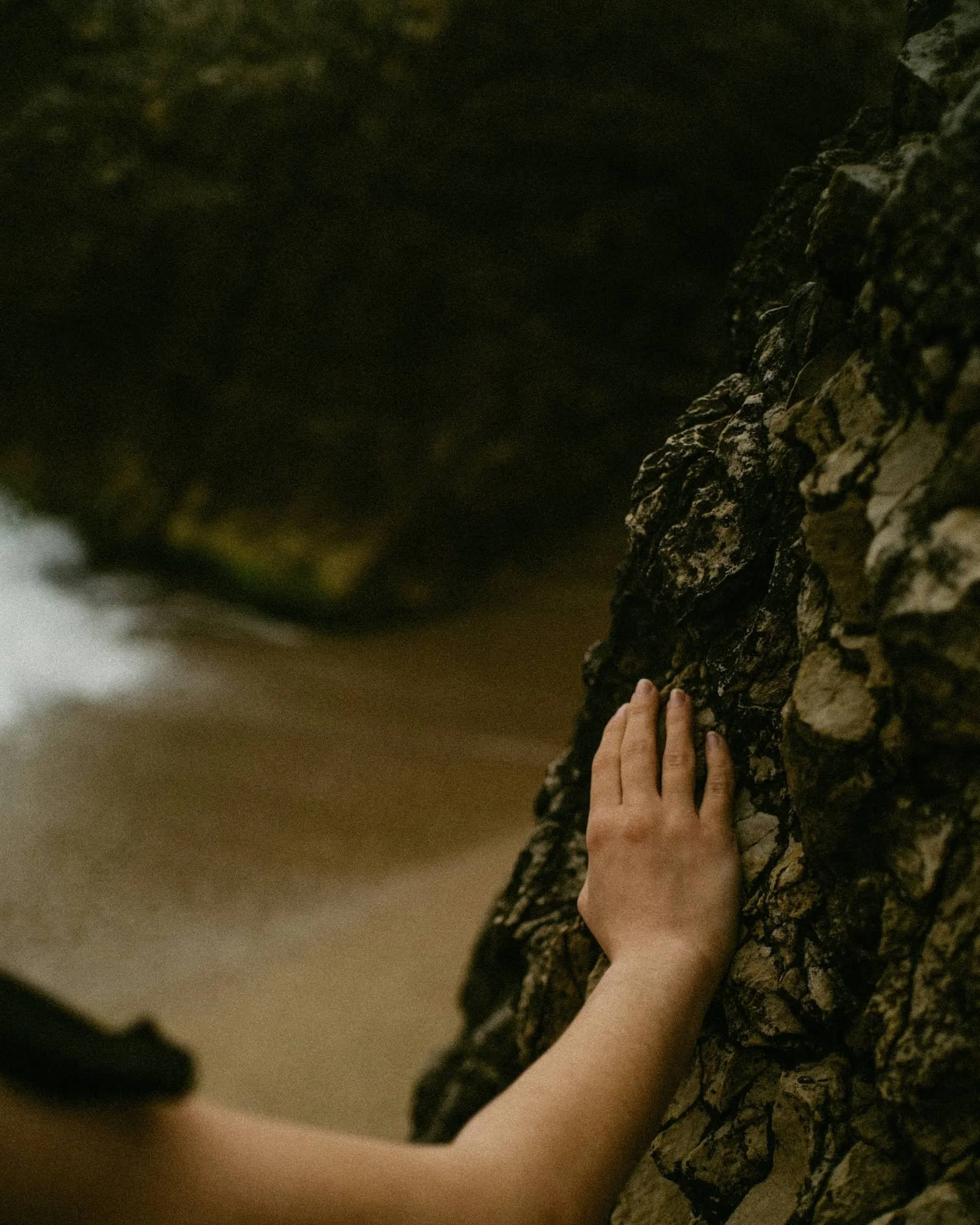 woman with hand on cliff at the beach