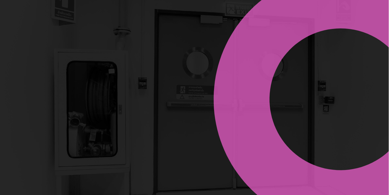 A darkened hospital corridor with an emergency exit door, a fire hose cabinet, and a purple graphic overlay.