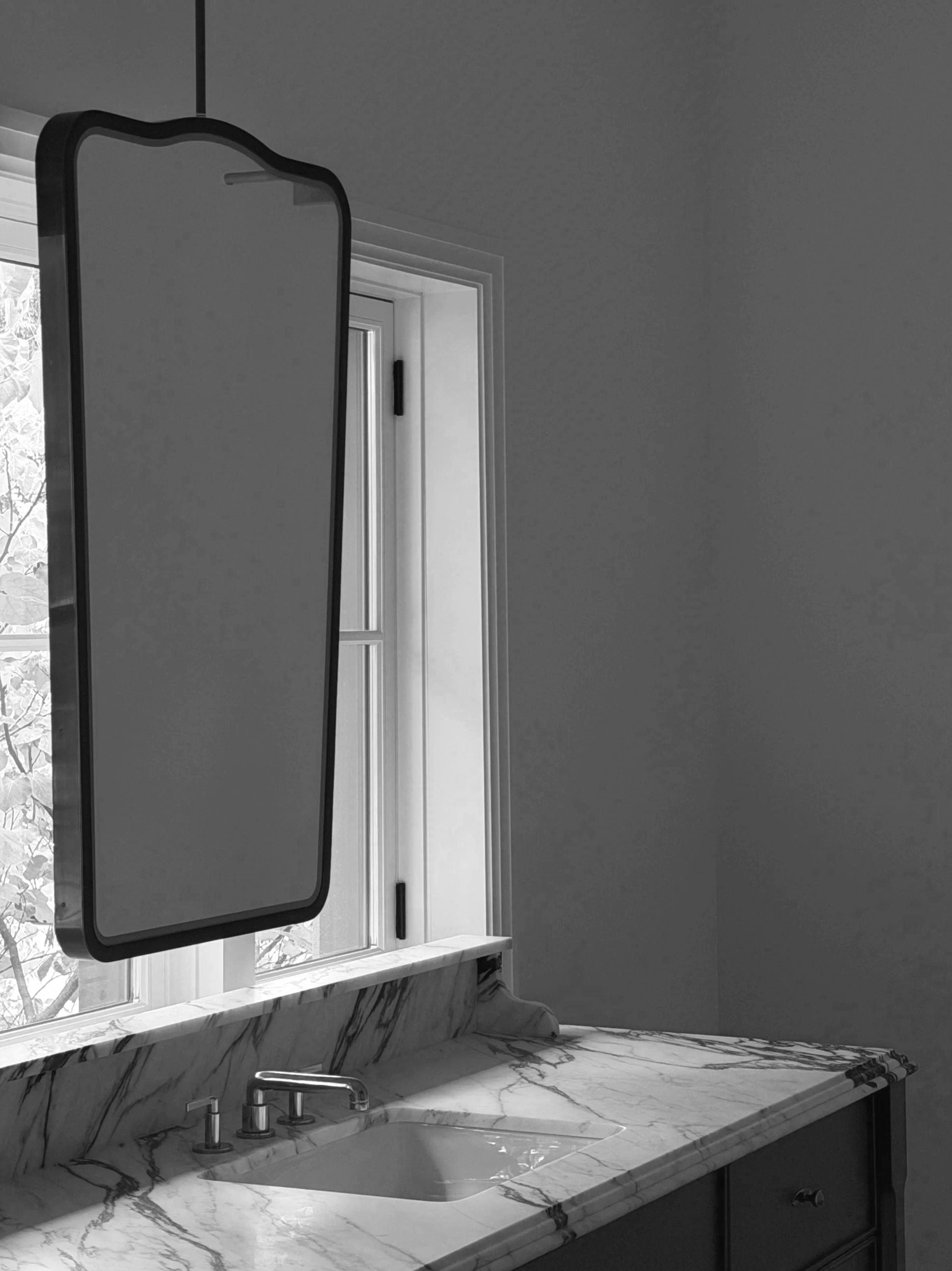 Custom ceiling-hung vanity mirror in a luxury modern bathroom with marble countertops