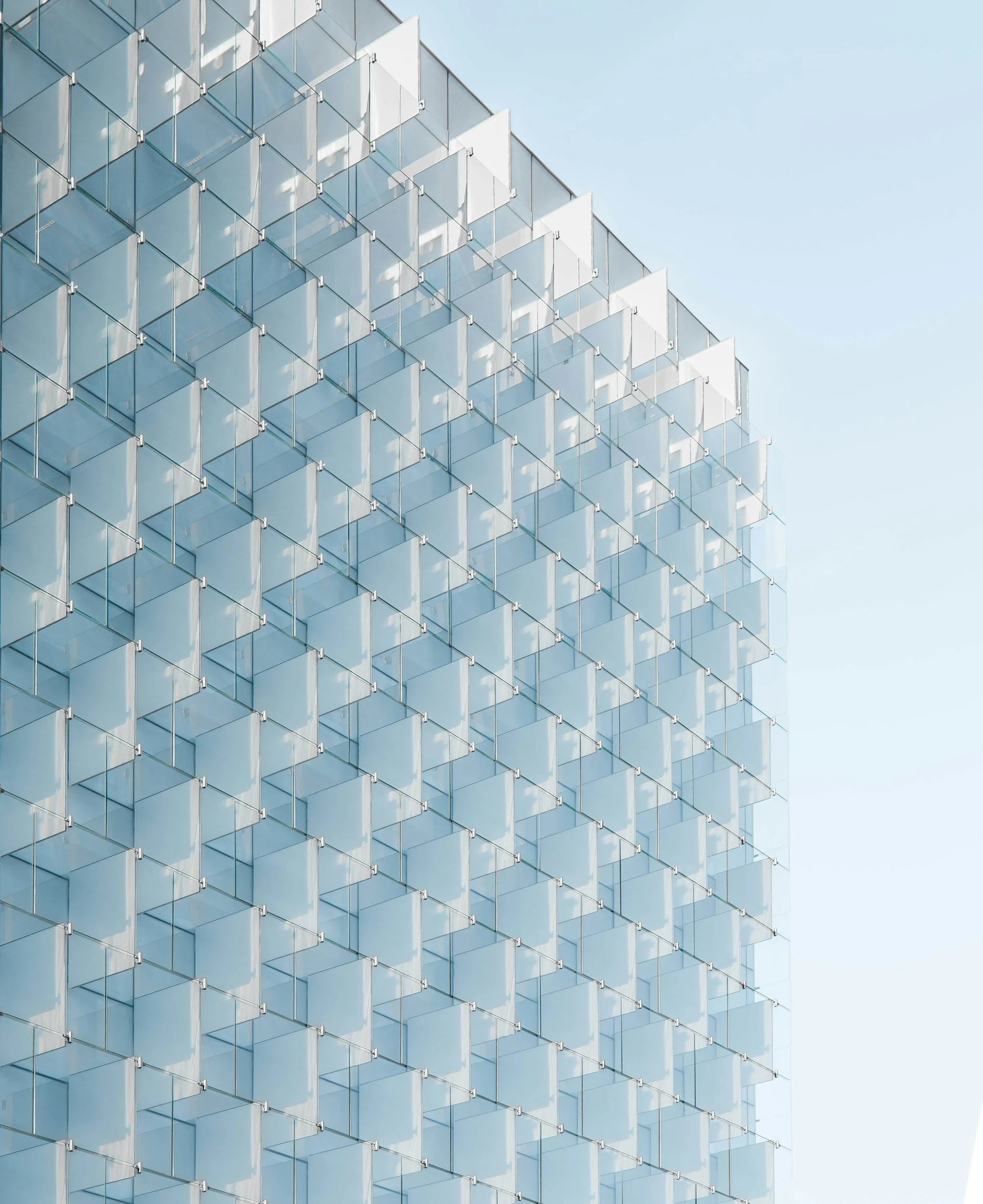 Modern glass building with a geometric pattern of cubes, reflecting the sky.